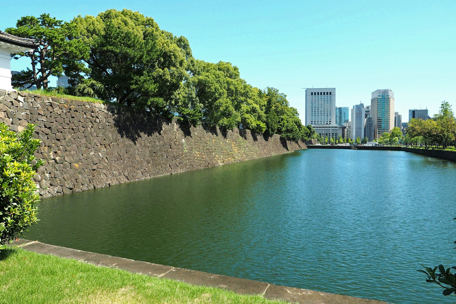 Blick auf die Schlossmauern von Tokio und den Graben mit Grünanlagen und modernen Gebäuden