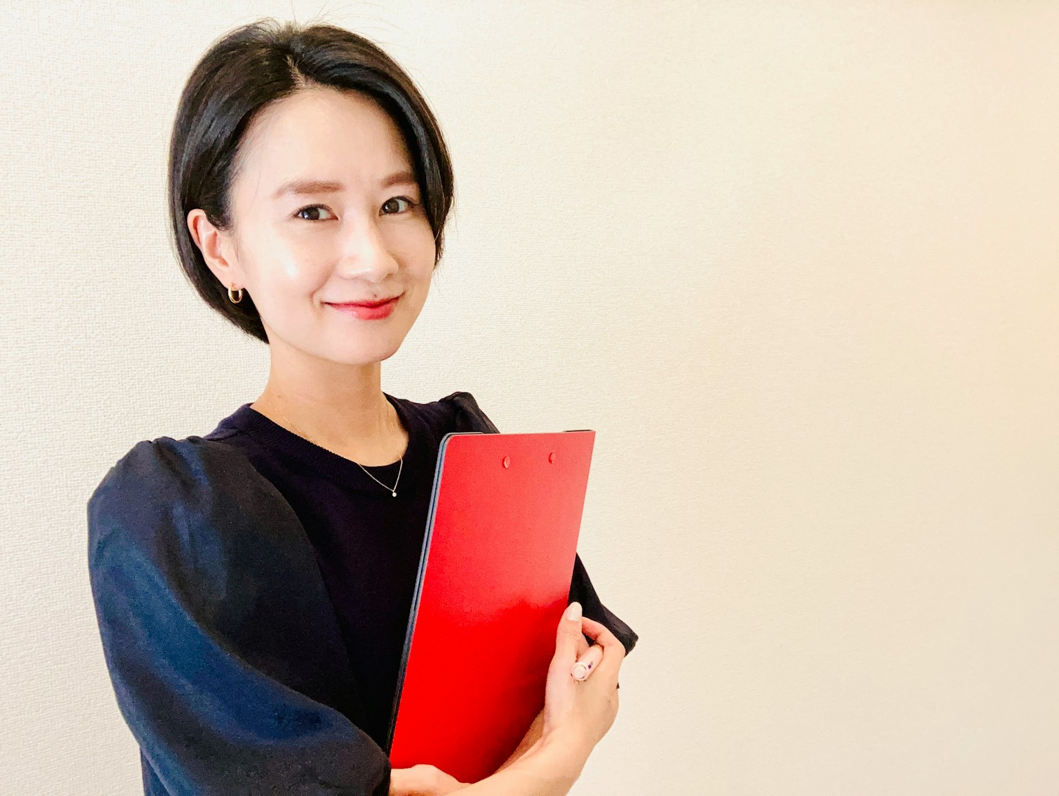 Wanita muda tersenyum sambil memegang folder merah
