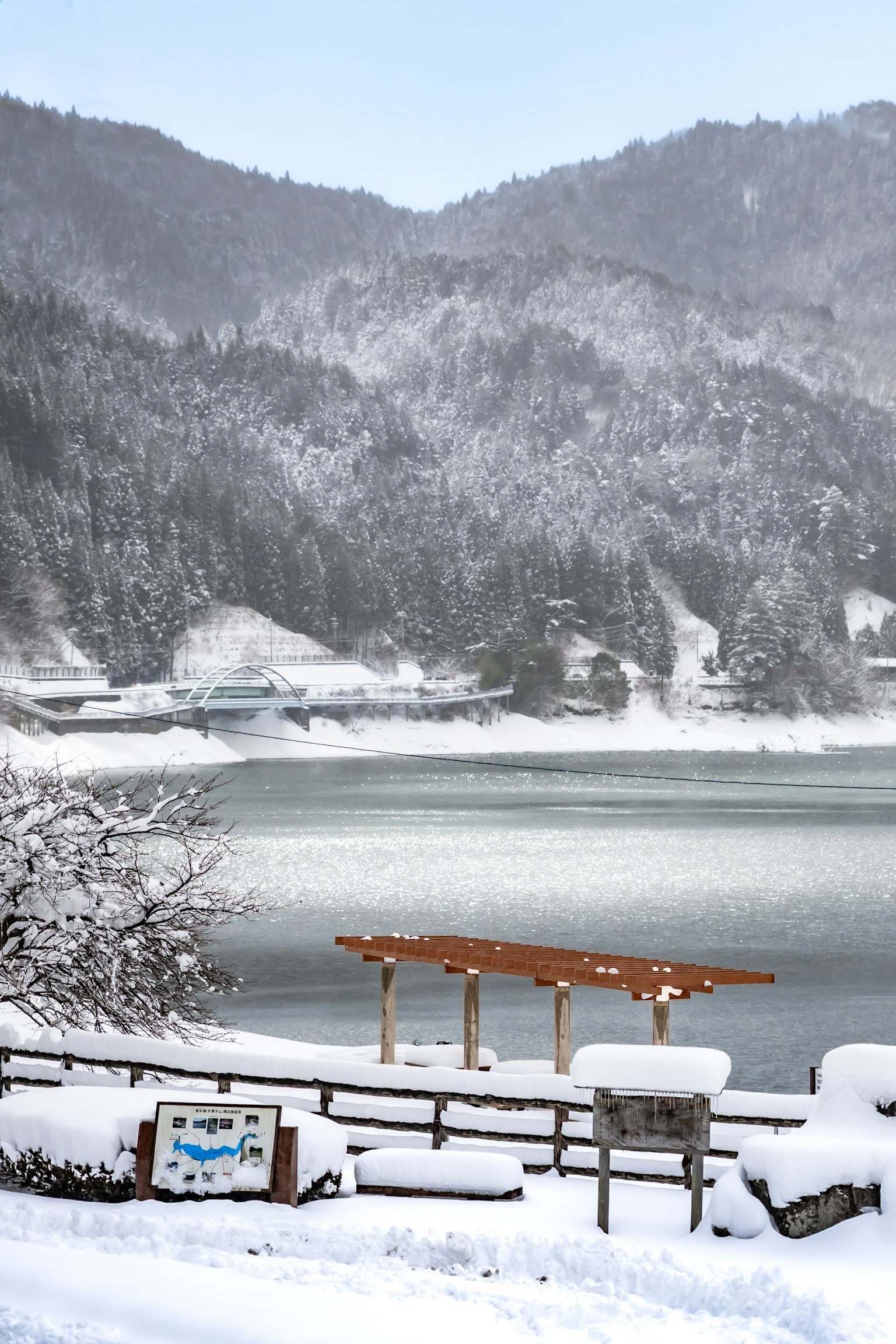 Lago e montagne innevate con un piccolo molo in legno e un cartello