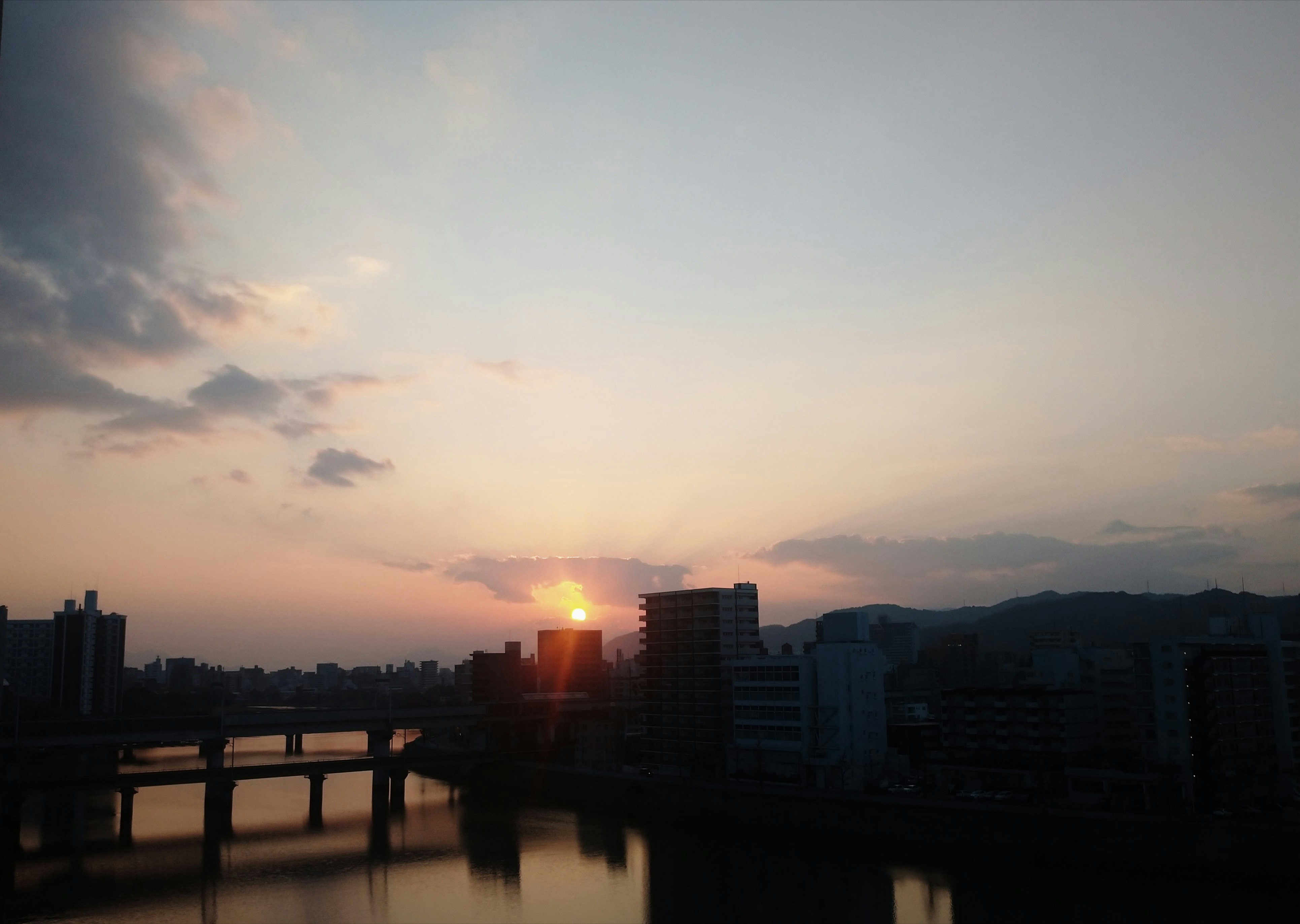 夕暮れの川沿いに広がる街並みと夕日