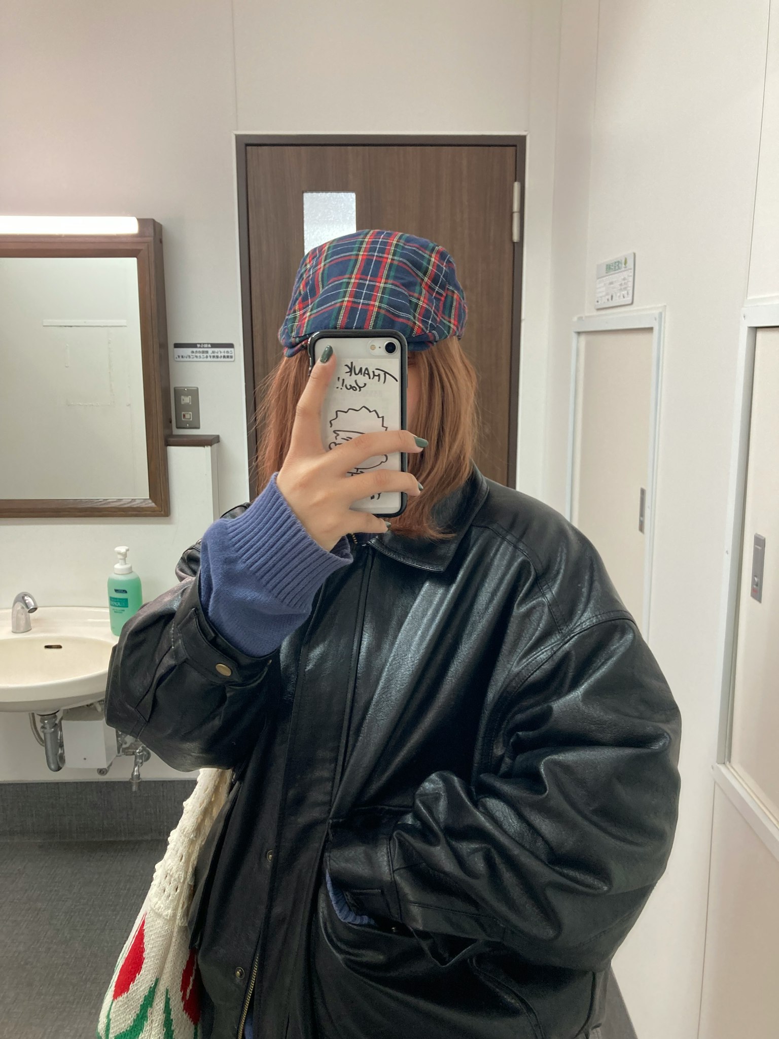 女人在镜子前自拍 穿着黑色皮夹克和格子帽