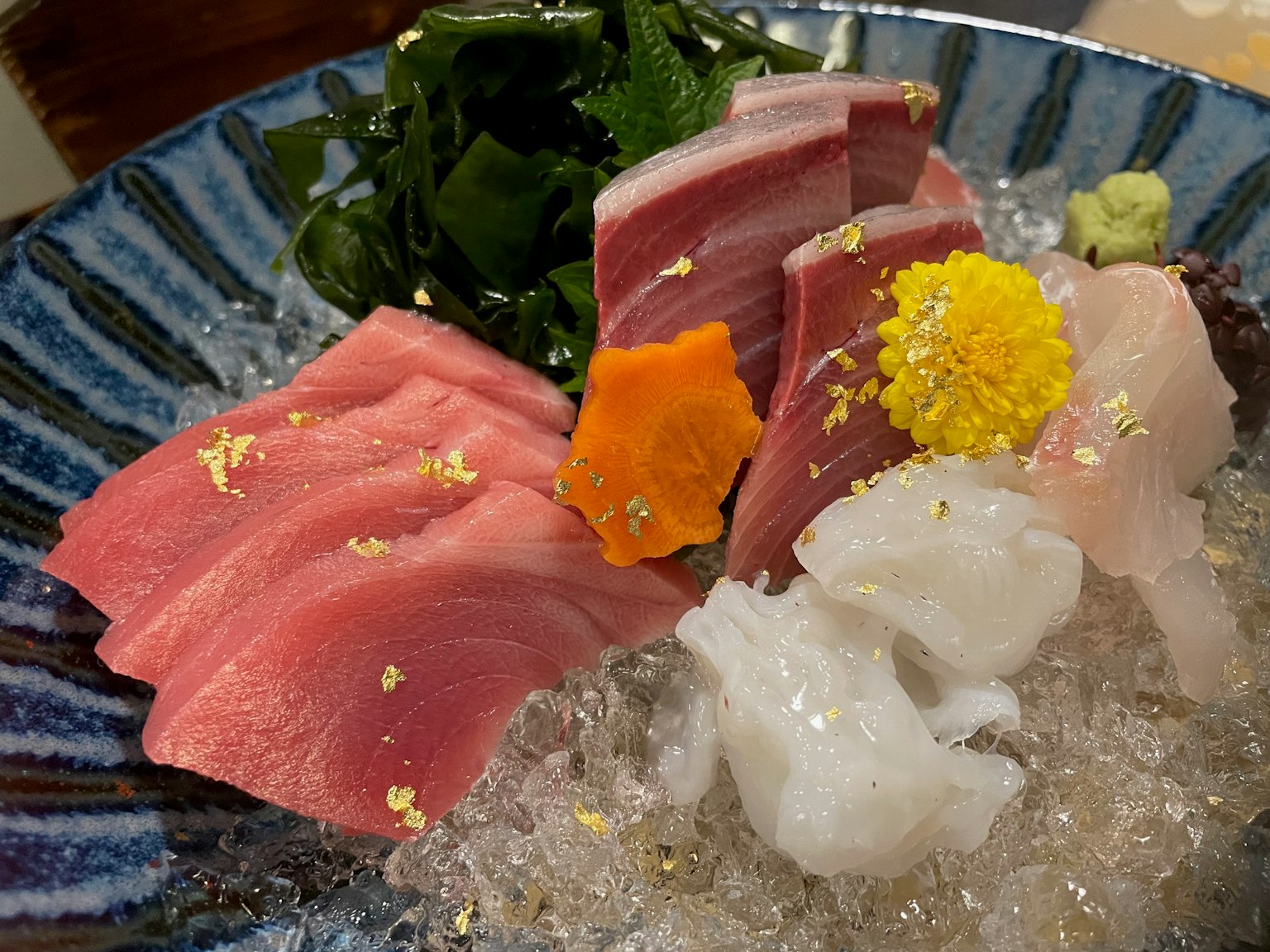 Piring sashimi yang indah dengan ikan segar dan dekorasi daun emas