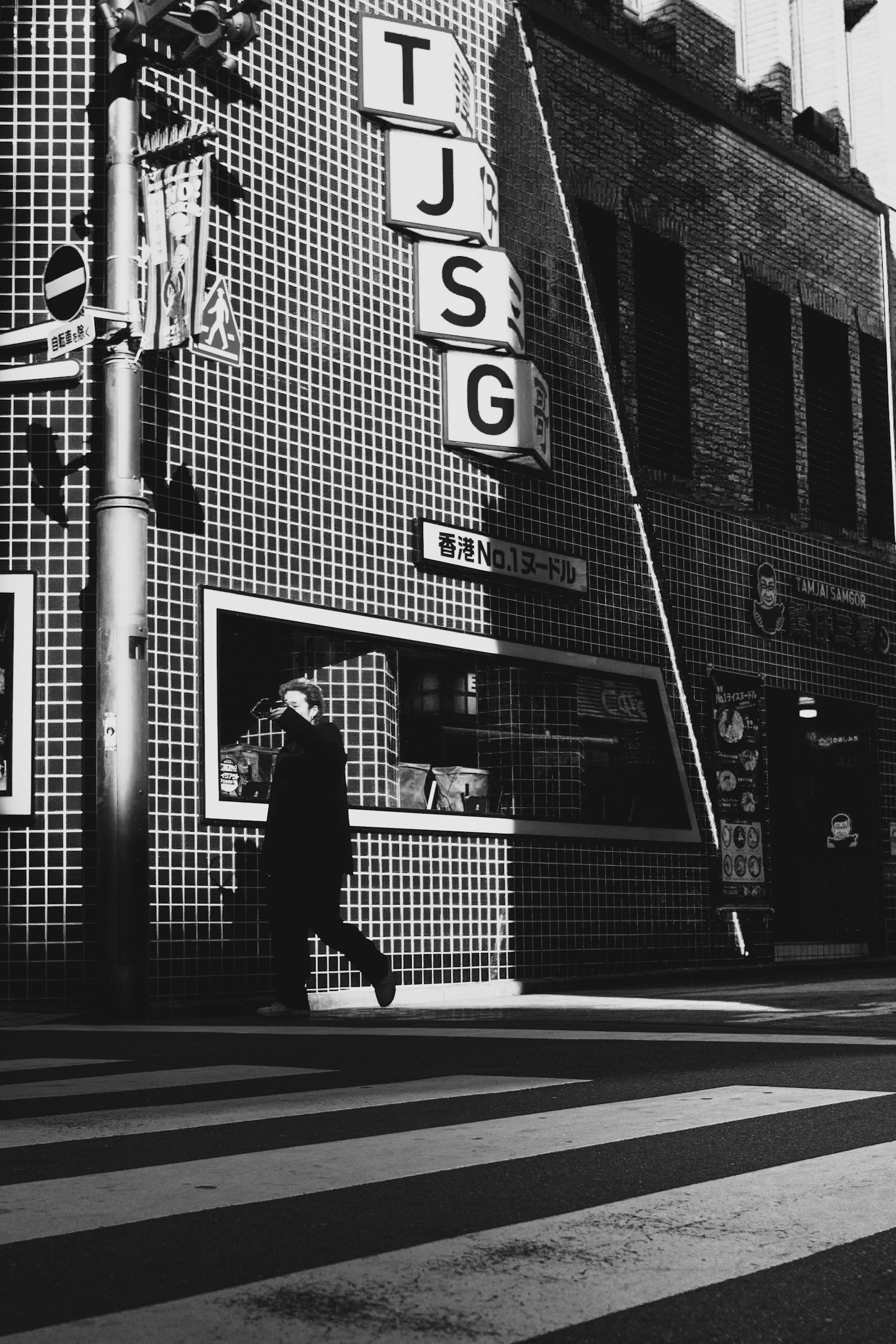 Angolo di strada in bianco e nero con insegna TJSG e una figura che attraversa la strada