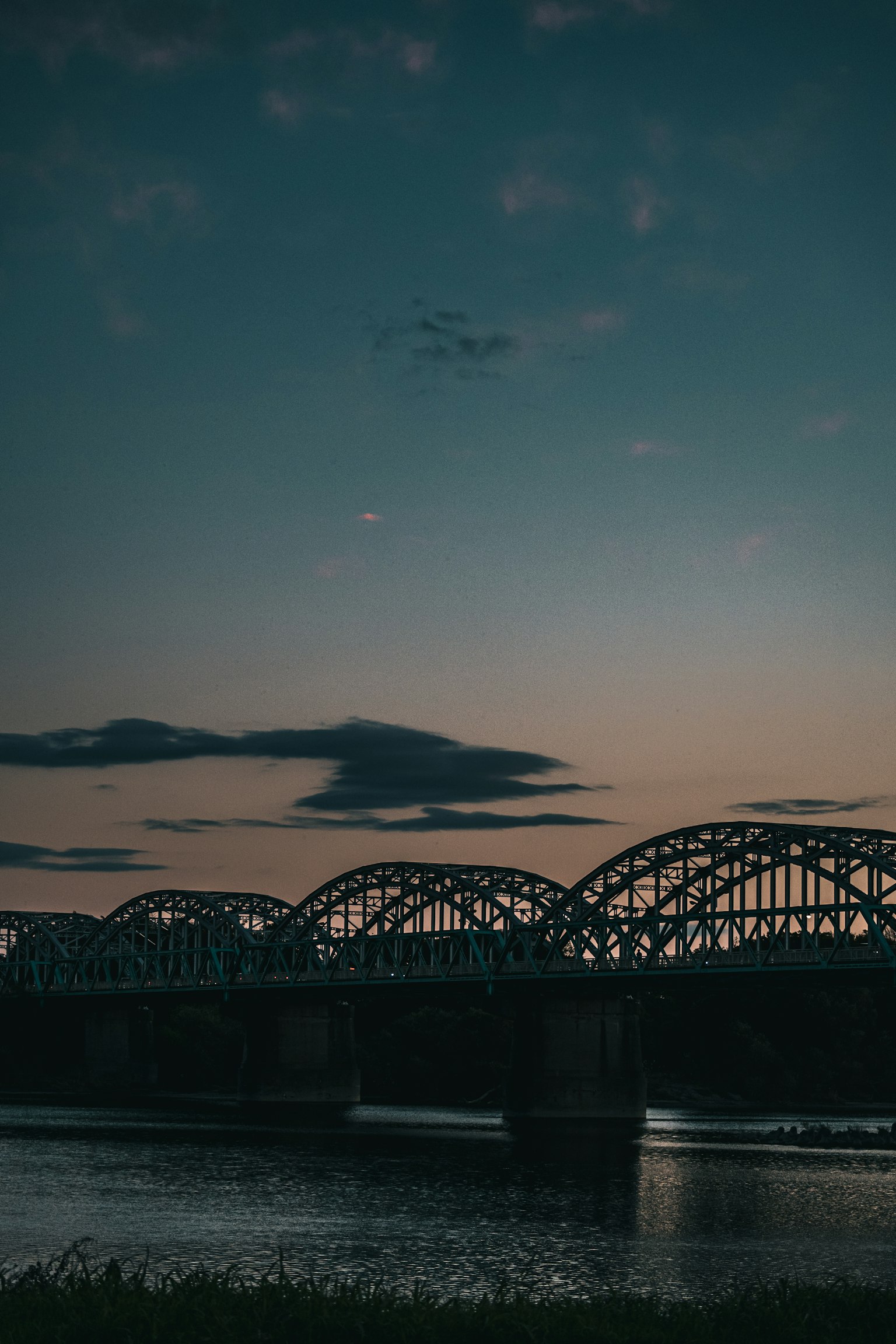 Silhouette of a beautiful arch bridge over a river at dusk