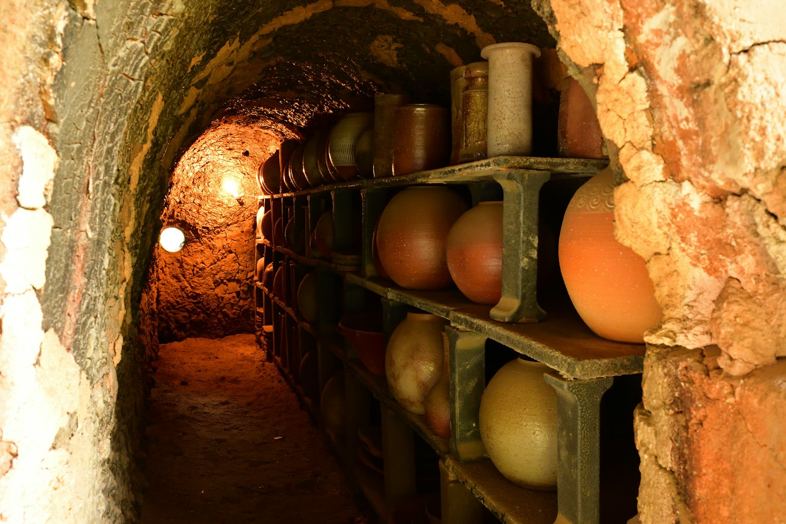 An underground tunnel featuring shelves of ceramic jars