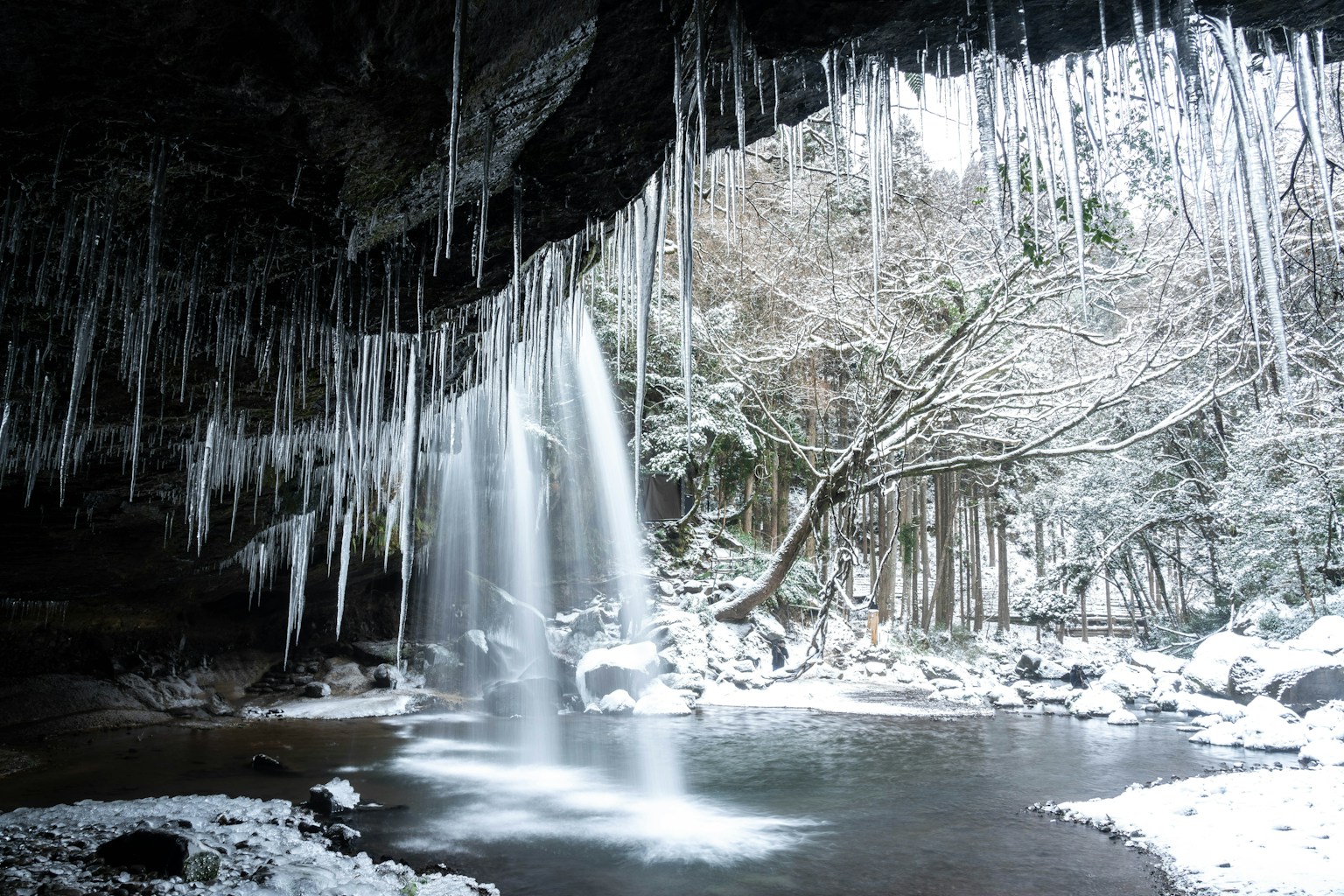 Pemandangan gua dengan air terjun bersalju dan stalaktit es