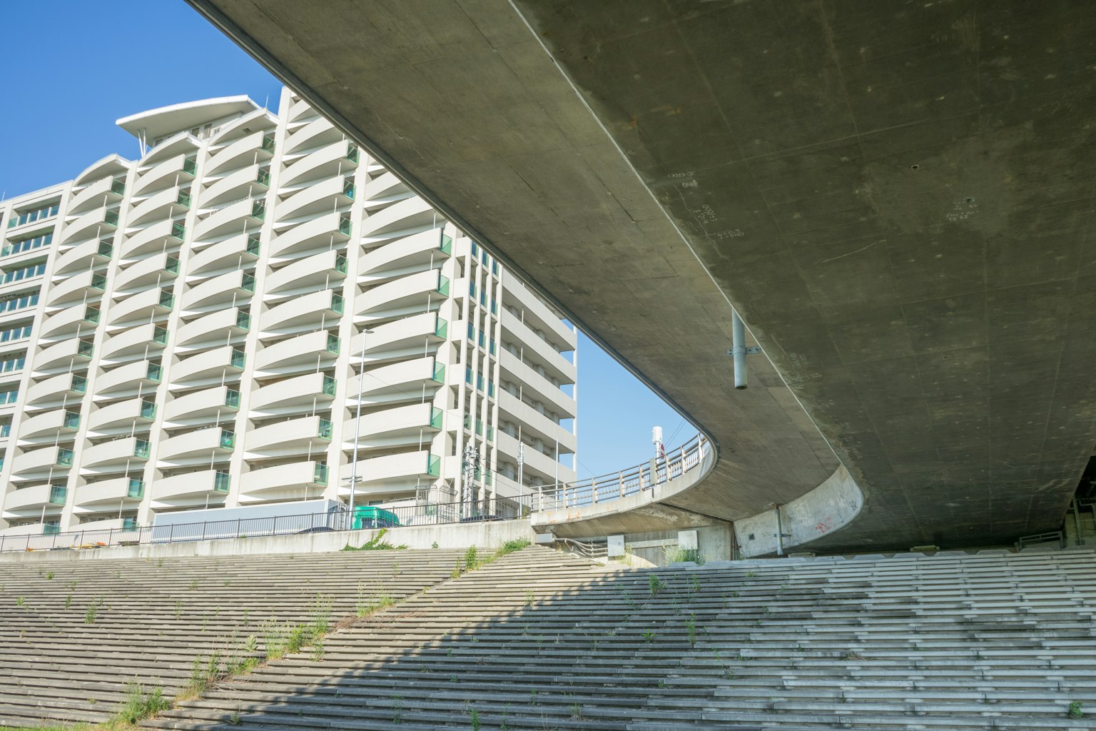 高層建築在混凝土橋下的景象，帶有樓梯