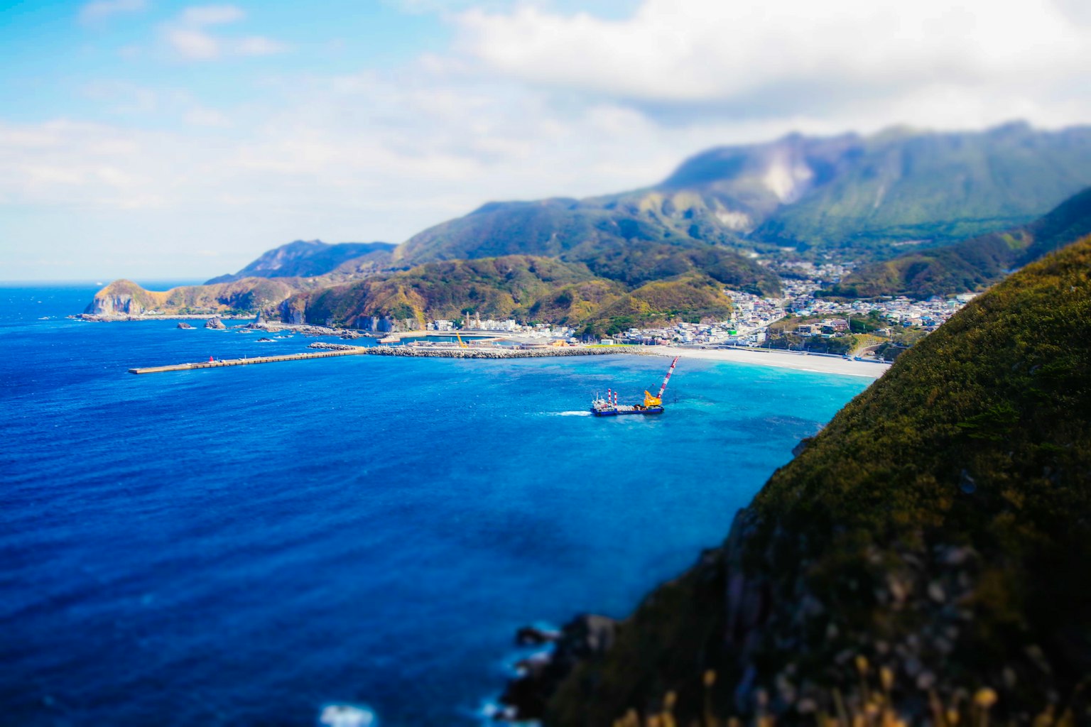 ทิวทัศน์ที่สวยงามของภูเขาและทะเล พื้นหลังเบลอมีน้ำสีฟ้าและเรือ