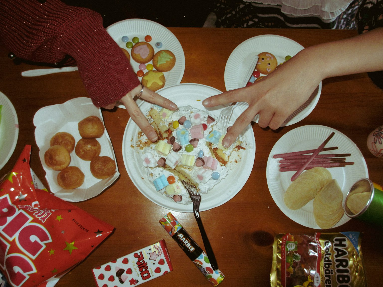 色彩繽紛的糖果和零食在桌子上，手做著和平手勢