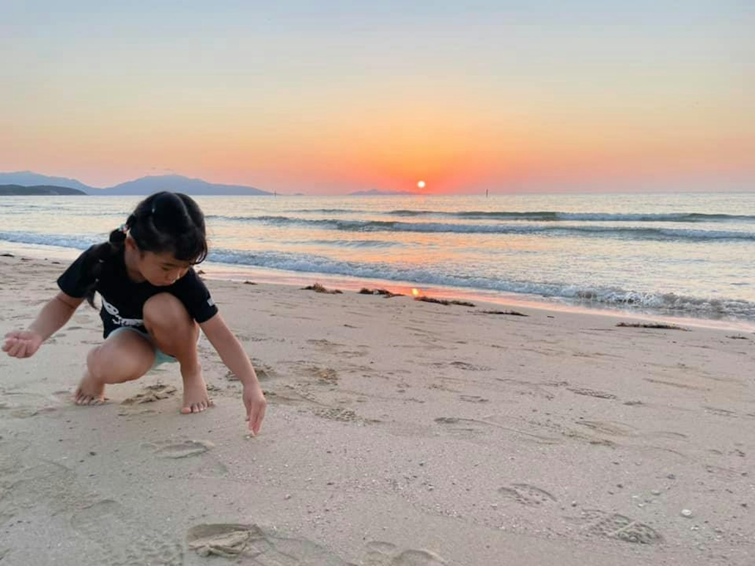 Niño jugando en la arena en la playa durante el atardecer