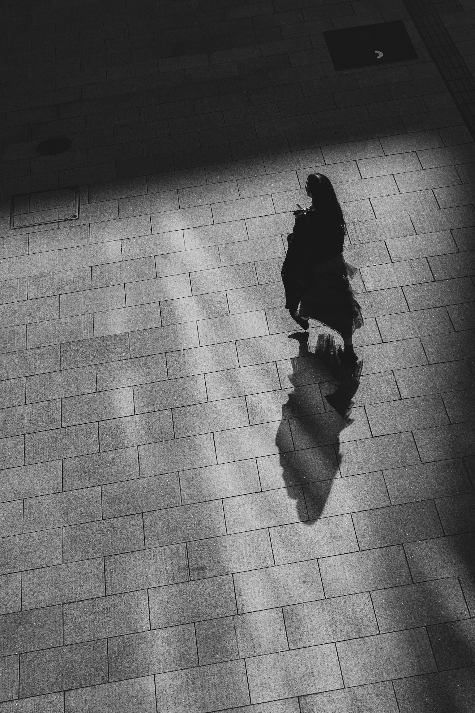 影の中を歩く人物のモノクロ写真
