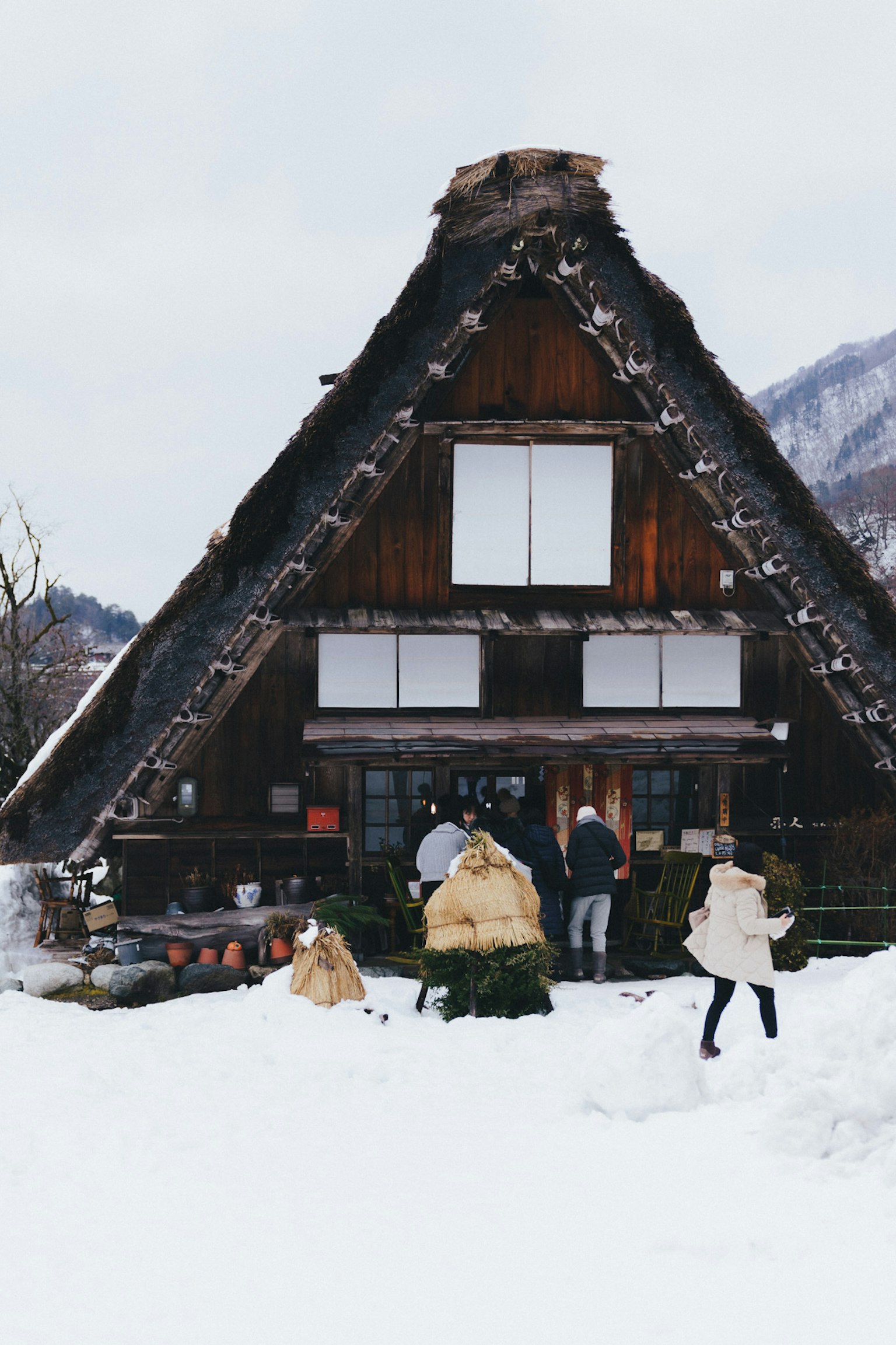 Maison traditionnelle gassho-zukuri recouverte de neige avec des touristes