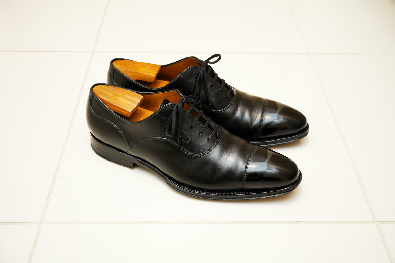 Black leather shoes placed on white tiles