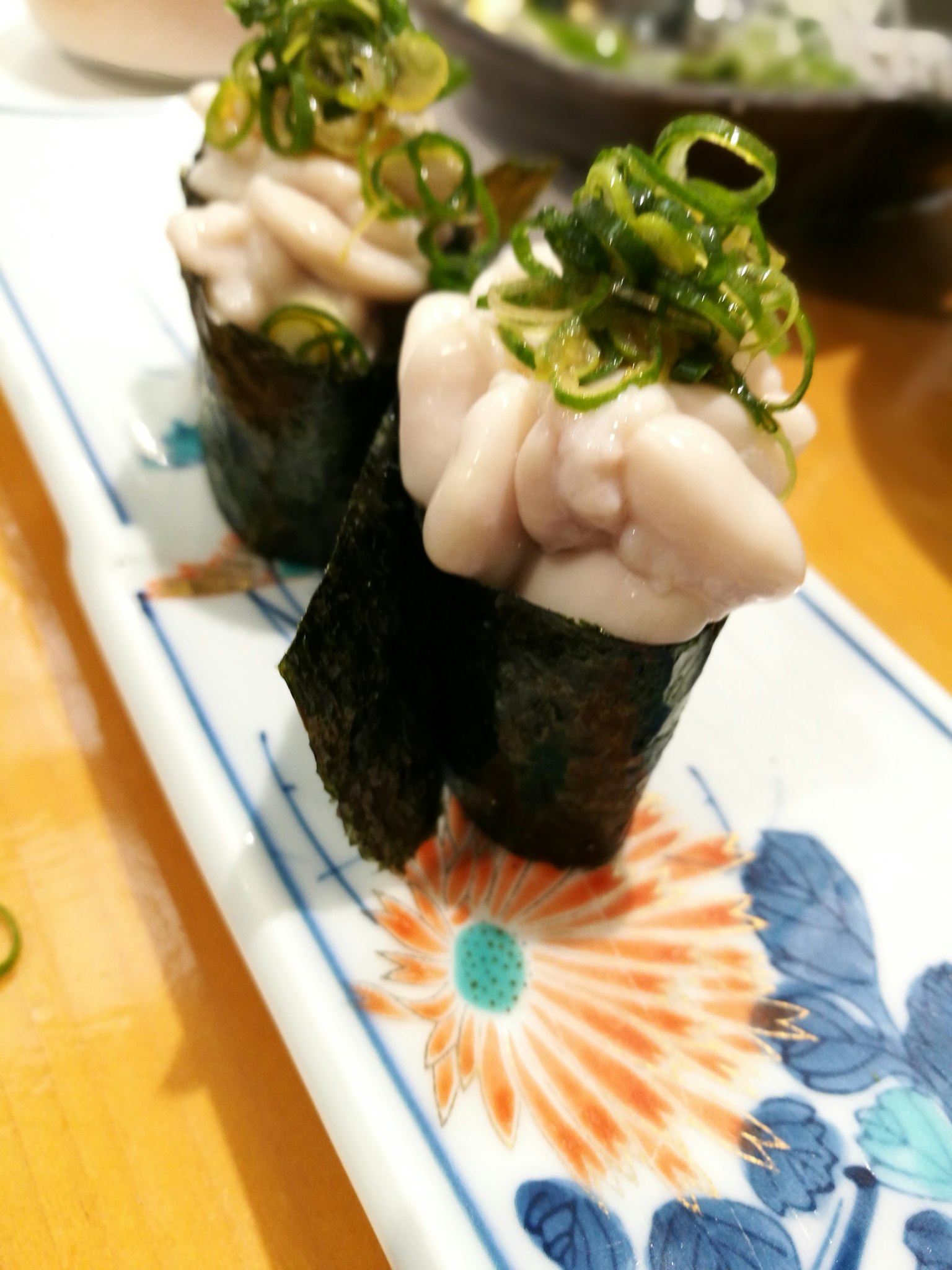 ซูชิที่มีท็อปปิ้งต้นหอมเสิร์ฟในจานตกแต่ง
