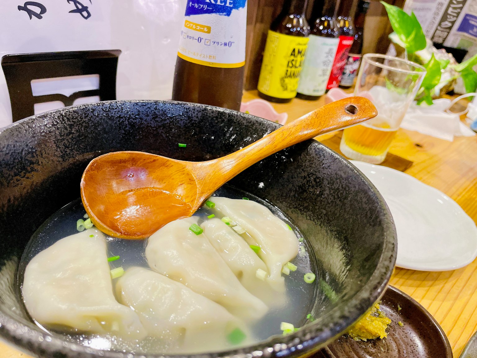 A bowl of dumplings in broth with a wooden spoon on a Japanese dining table