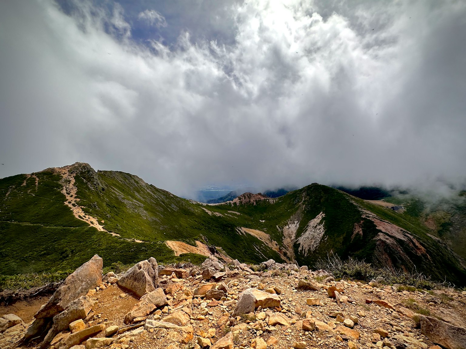 View from a mountain peak with clouds and green hills