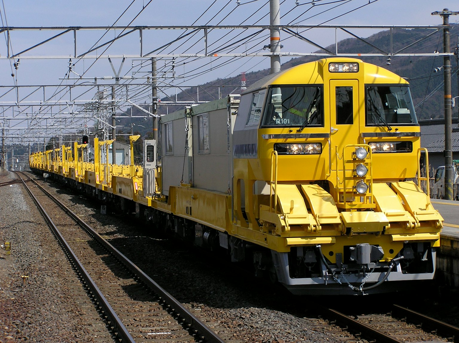 Kereta pemeliharaan rel berwarna kuning di atas rel