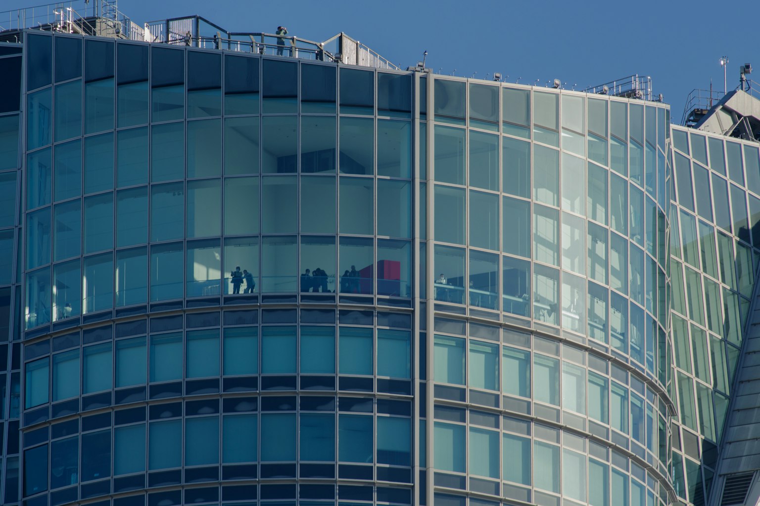 Una sección de un edificio alto de vidrio con personas visibles en el interior
