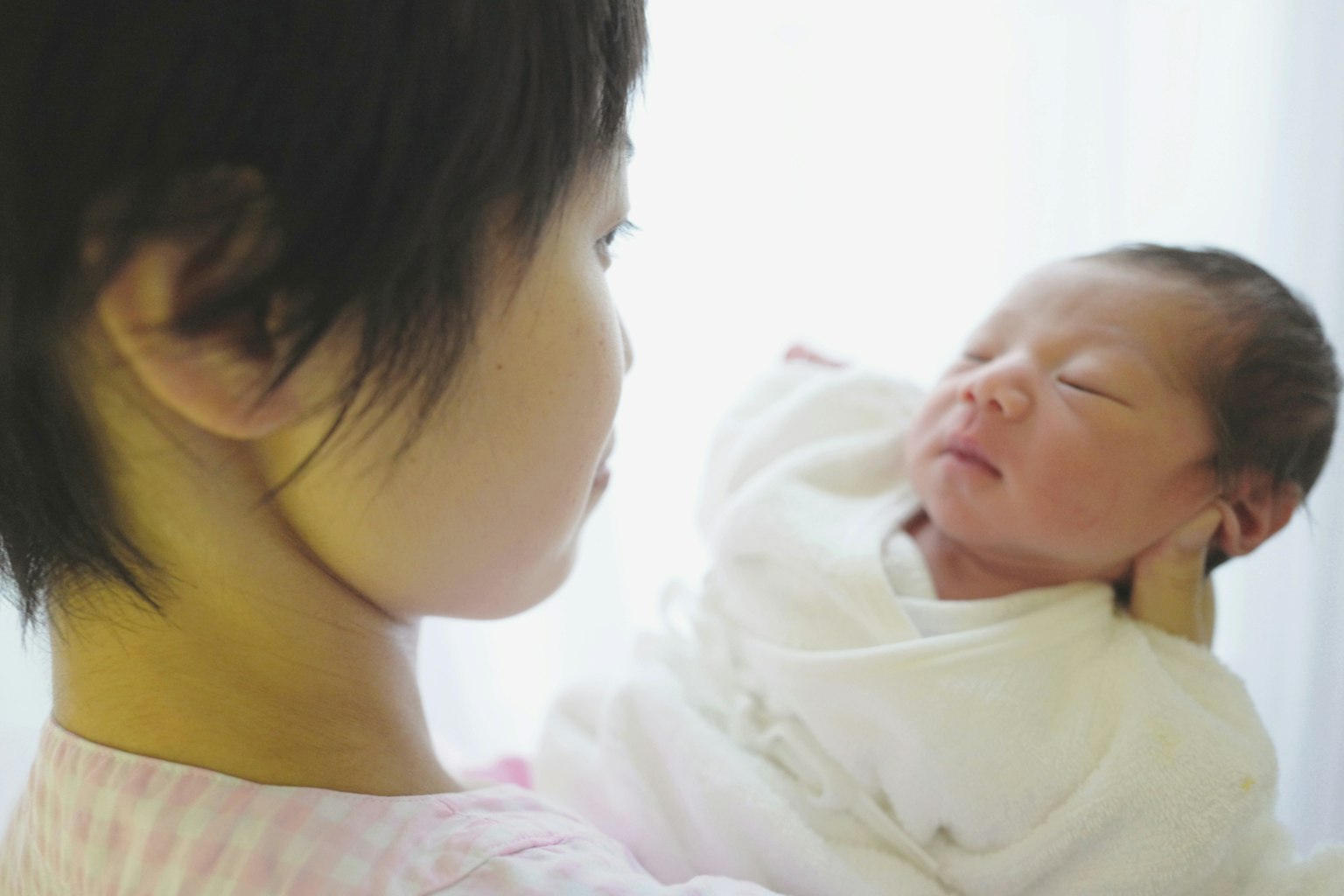 孩子抱着婴儿，窗外柔和的光线