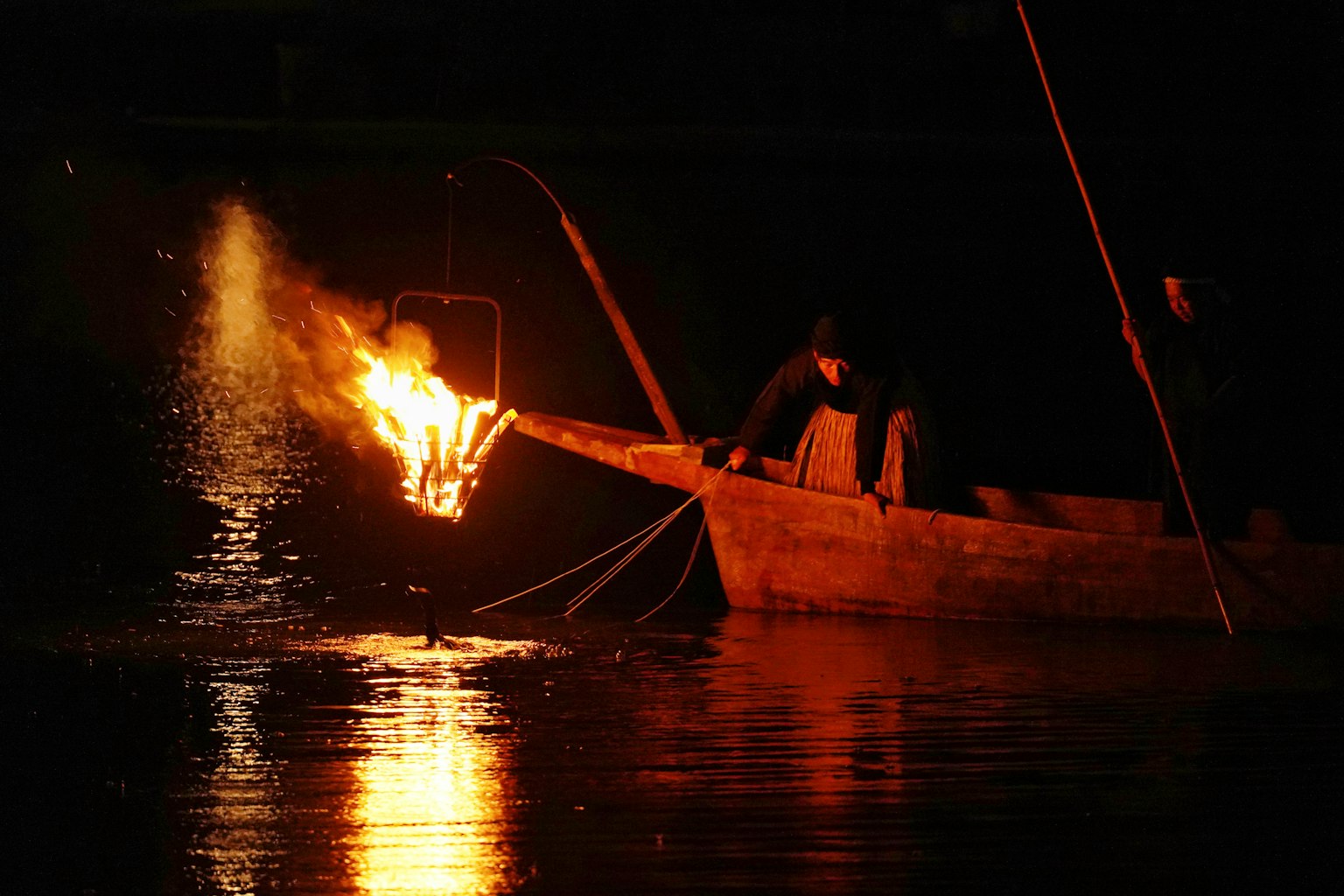 夜の川で漁をする漁師が火を灯した小舟