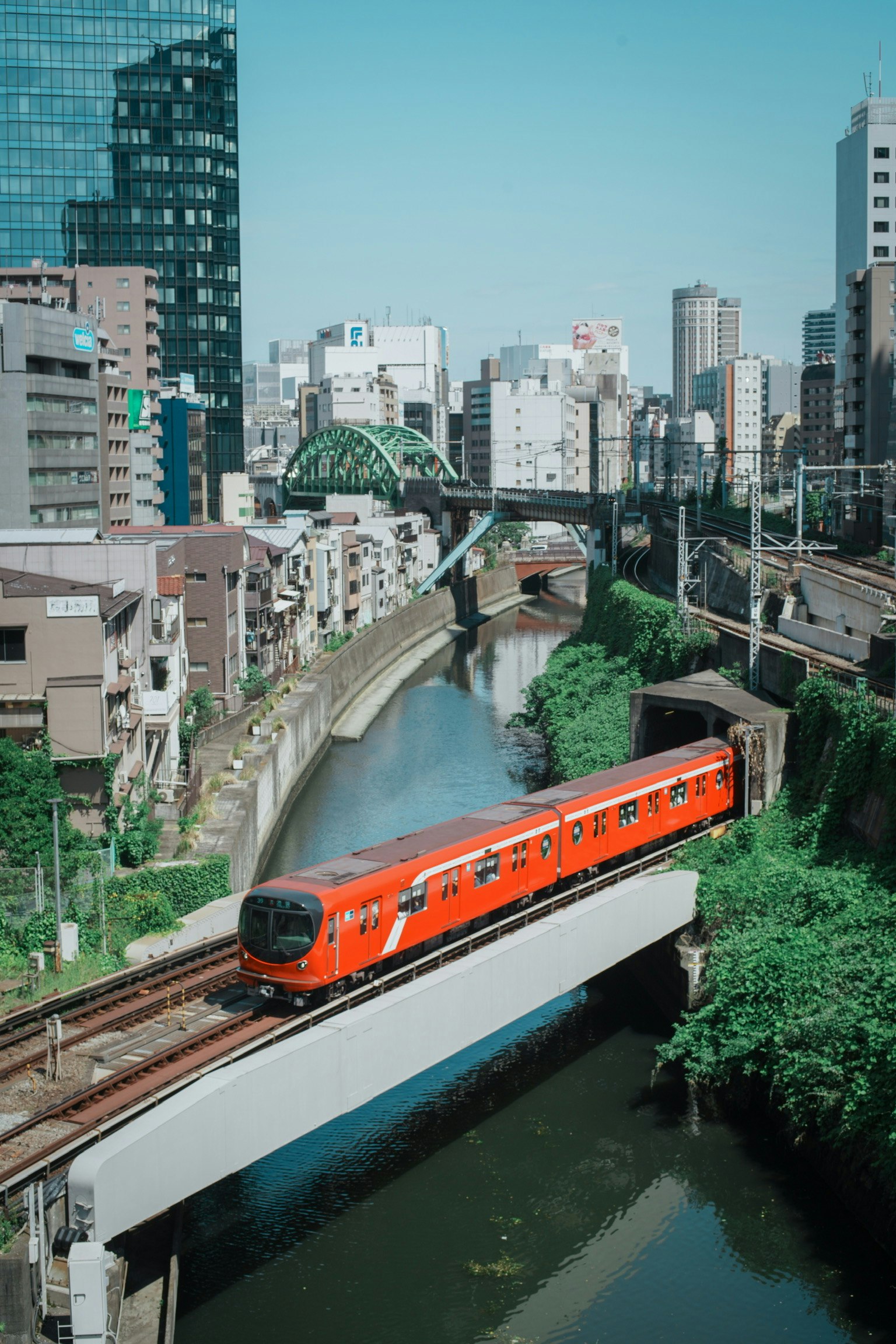 運河を走るオレンジの列車と高層ビル群の都市景観
