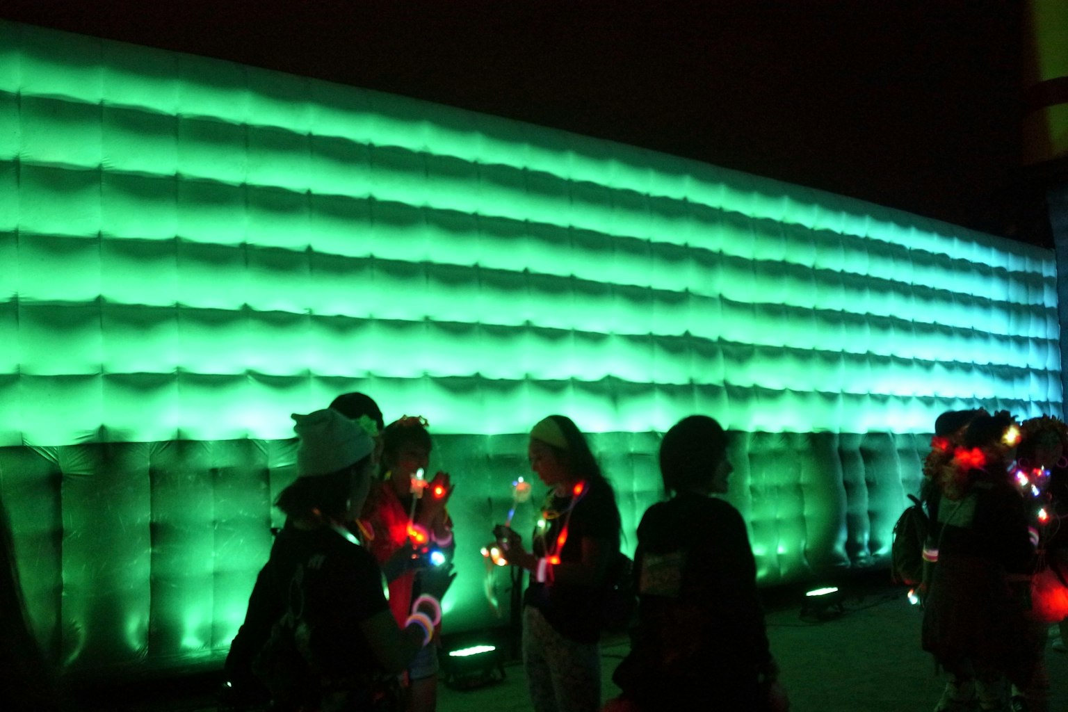 Silhouettes of people in front of a glowing green wall