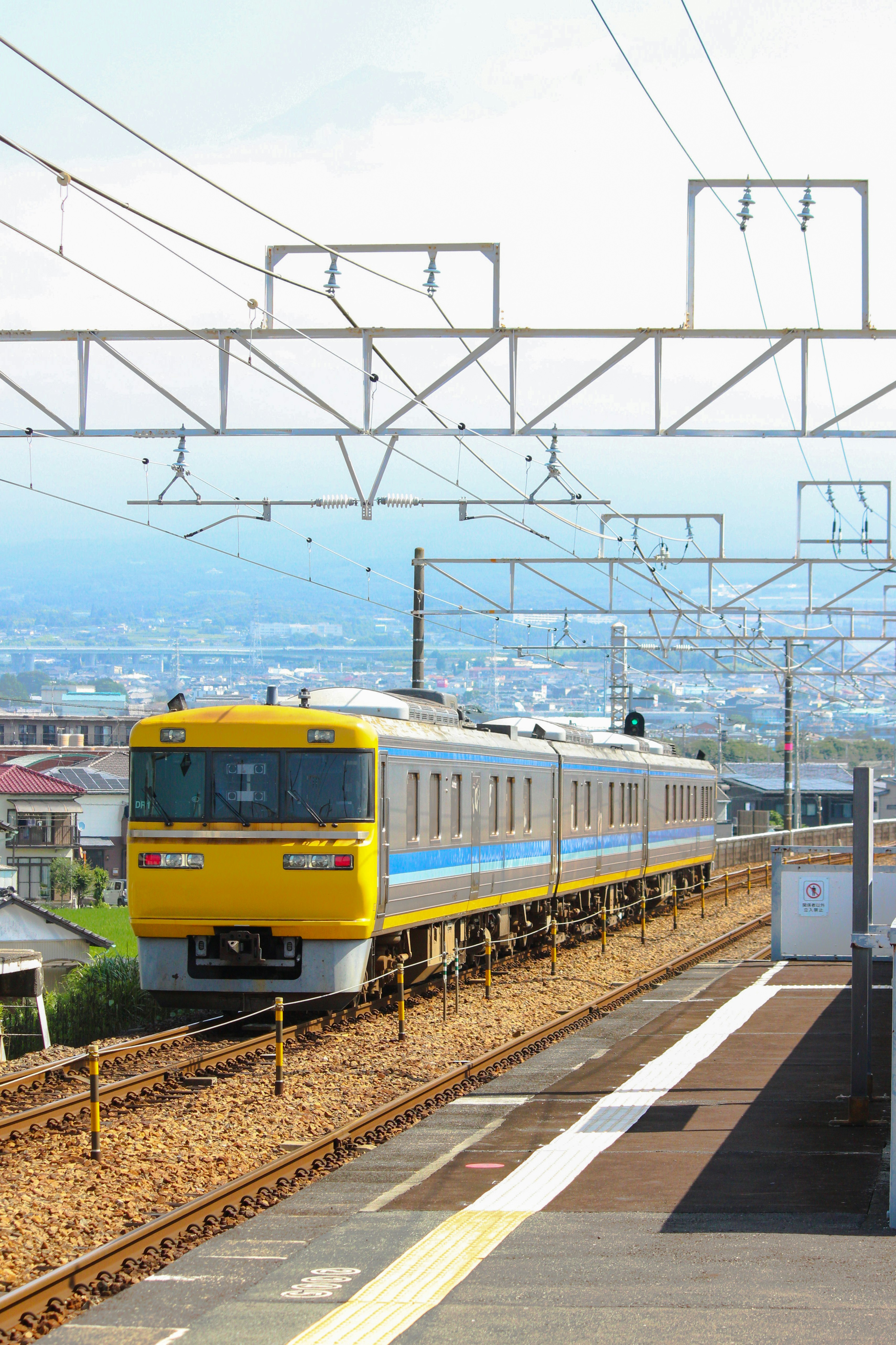 駅を通過する黄色い電車の車両と線路