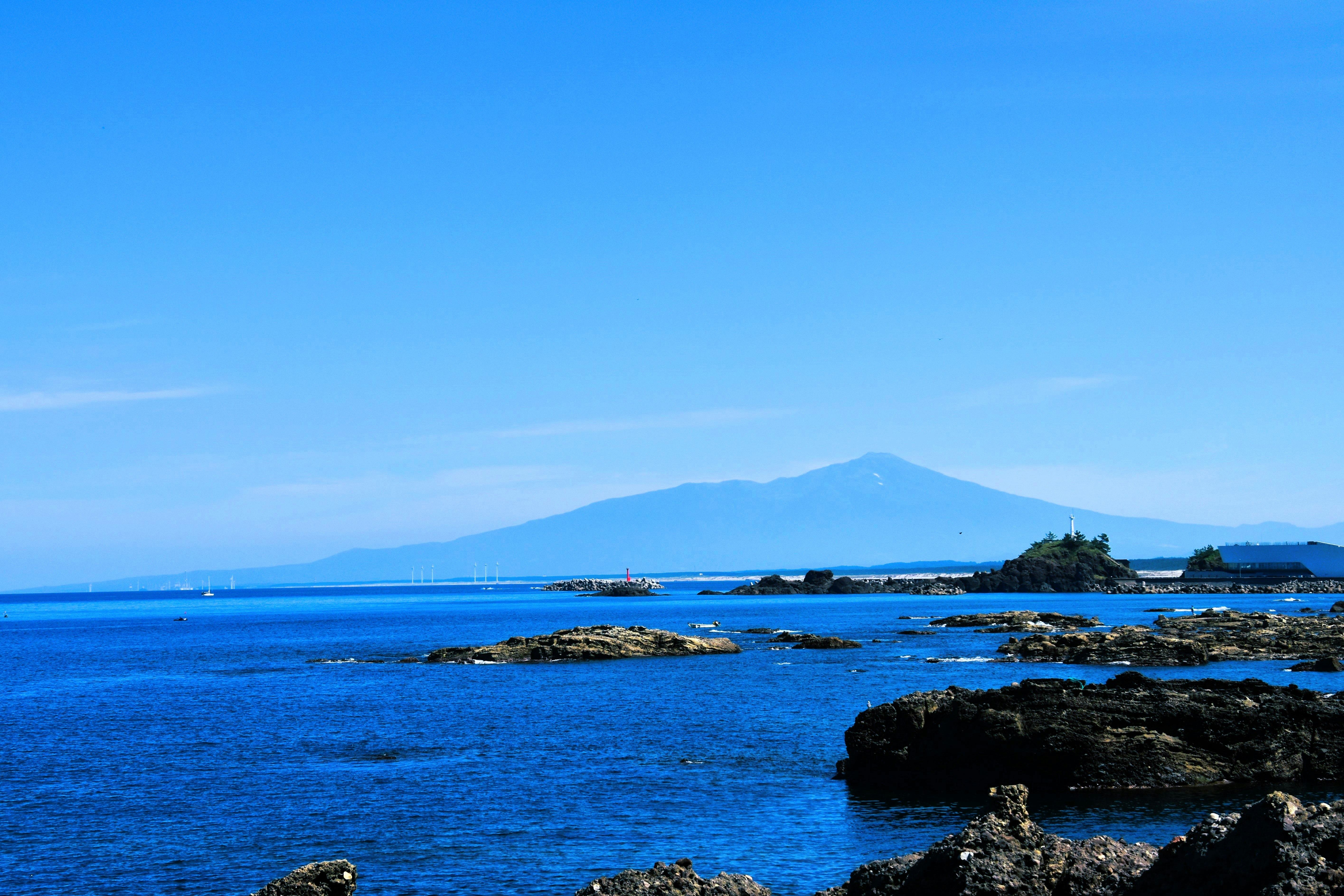 青い海と岩礁、遠くに山と岬の景色