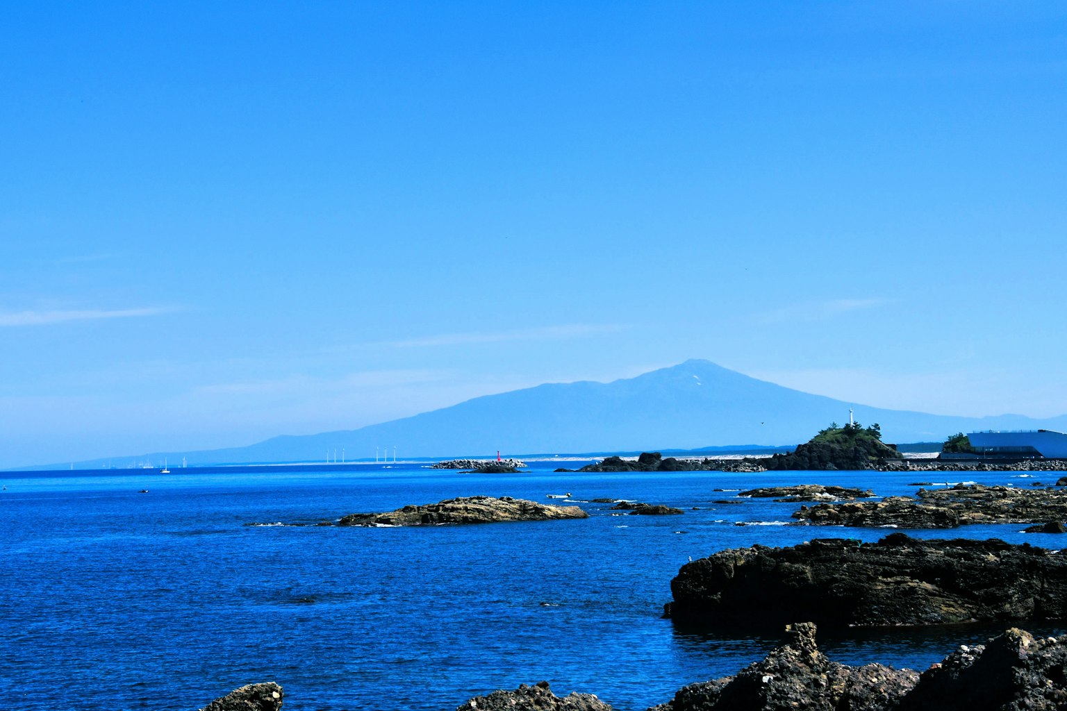 Blue ocean with rocks and a distant mountain