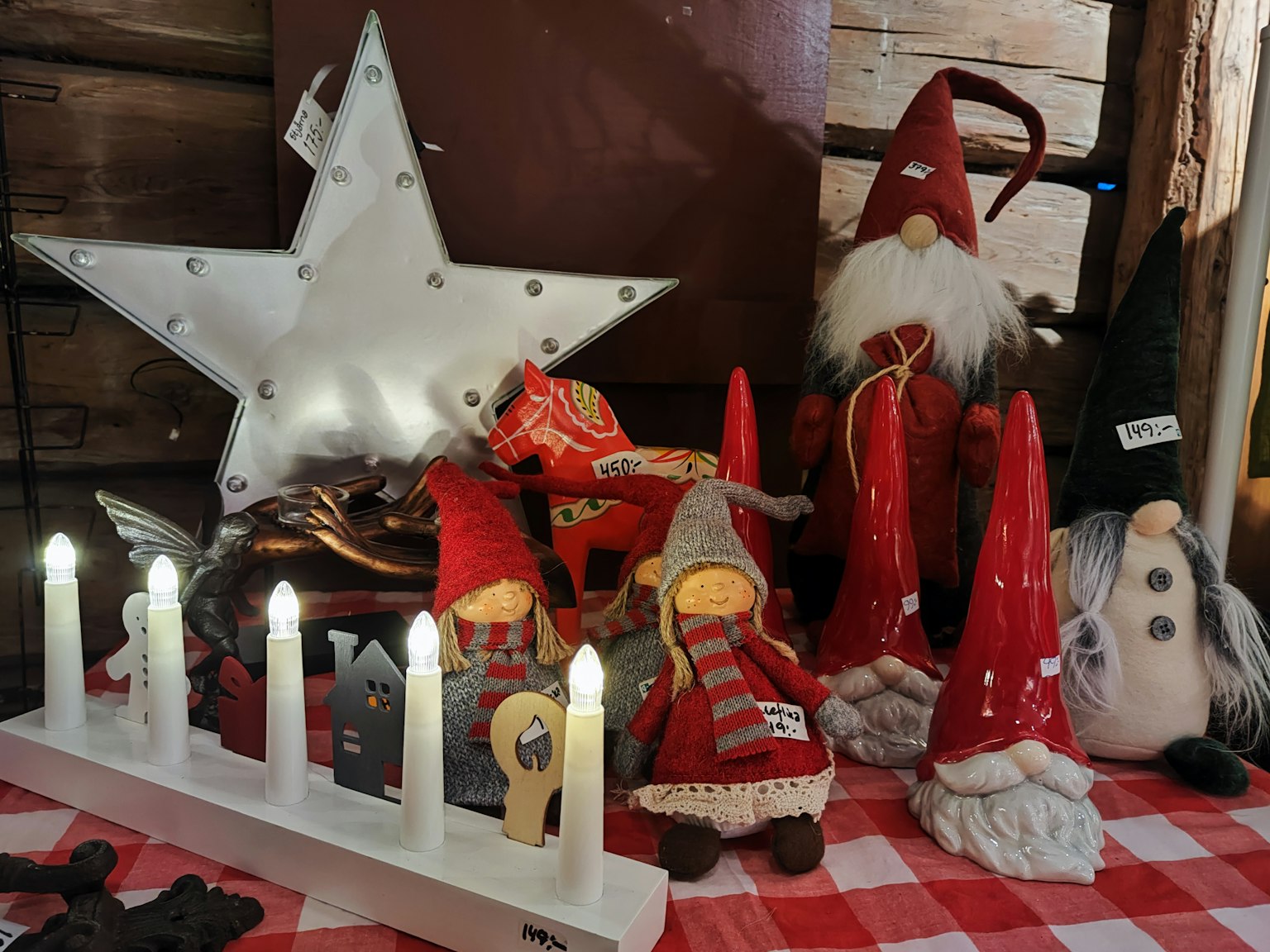 Dekorasi Natal dan boneka yang dipajang di atas taplak meja kotak merah dan putih