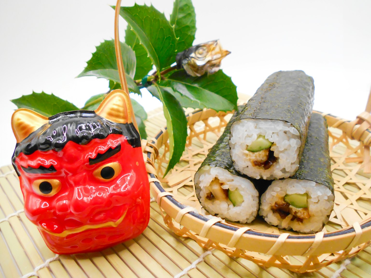 A red demon figurine next to sushi rolls on a decorative plate
