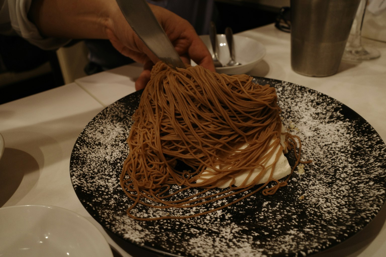 Una mano sosteniendo un tenedor sobre un postre Mont Blanc cubierto con crema de castañas fina