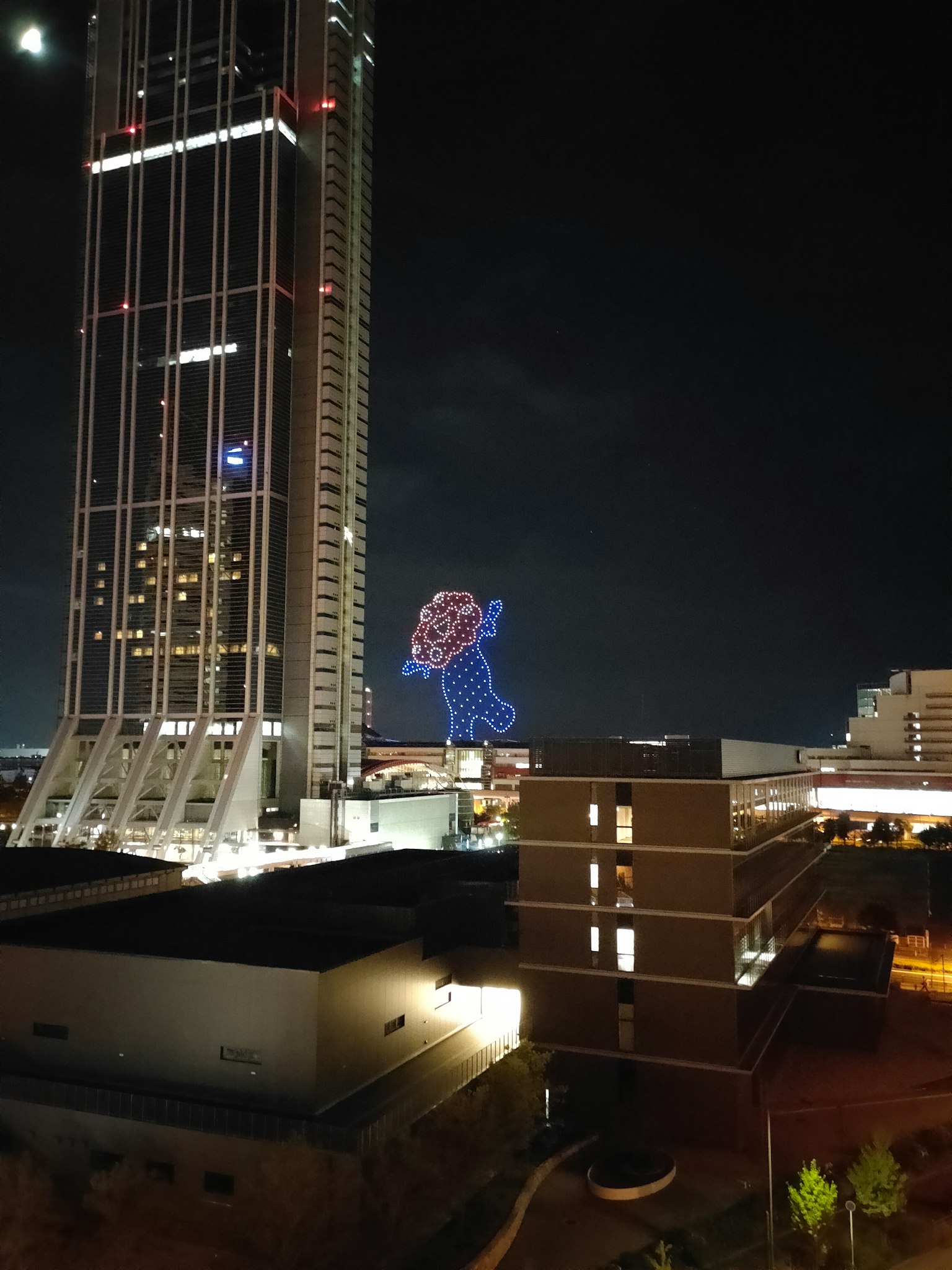 夜空中大型发光角色与摩天大楼