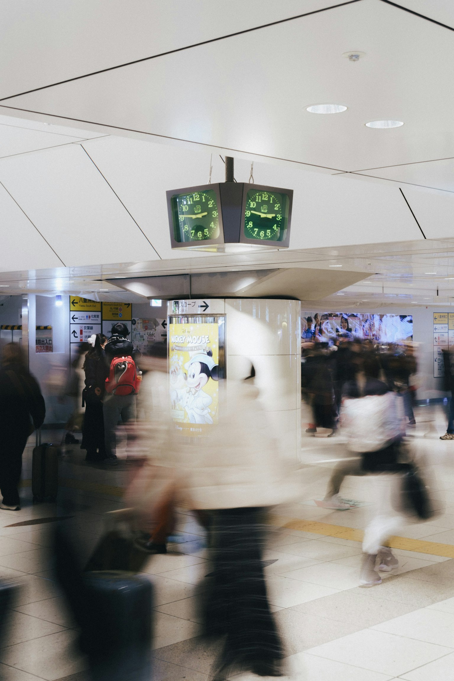 Cảnh ga tàu bận rộn với mọi người di chuyển và đồng hồ hiển thị