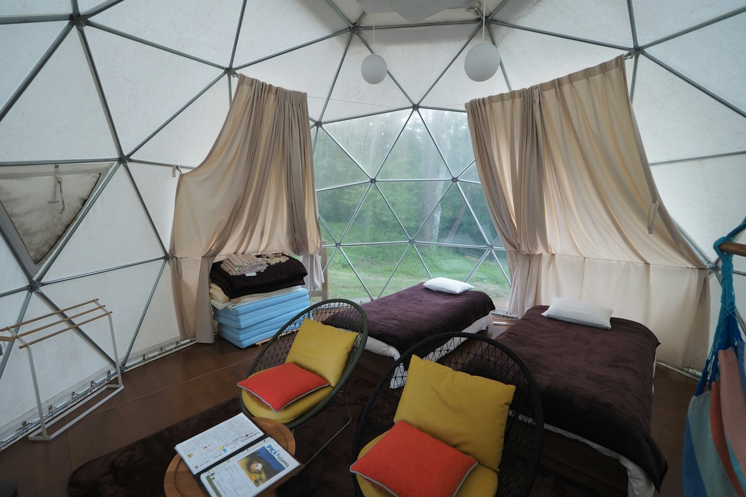 Interno di un dome geodetico con due letti e cuscini colorati disposti