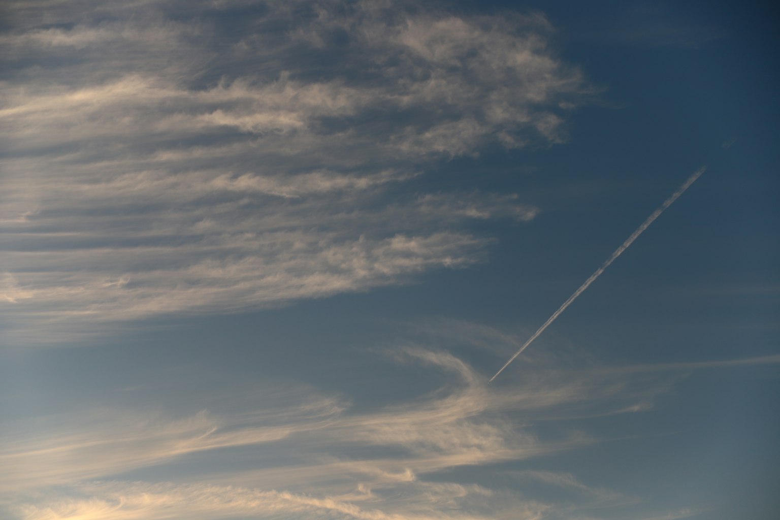寧靜的天空中有稀疏的雲和可見的飛機尾跡
