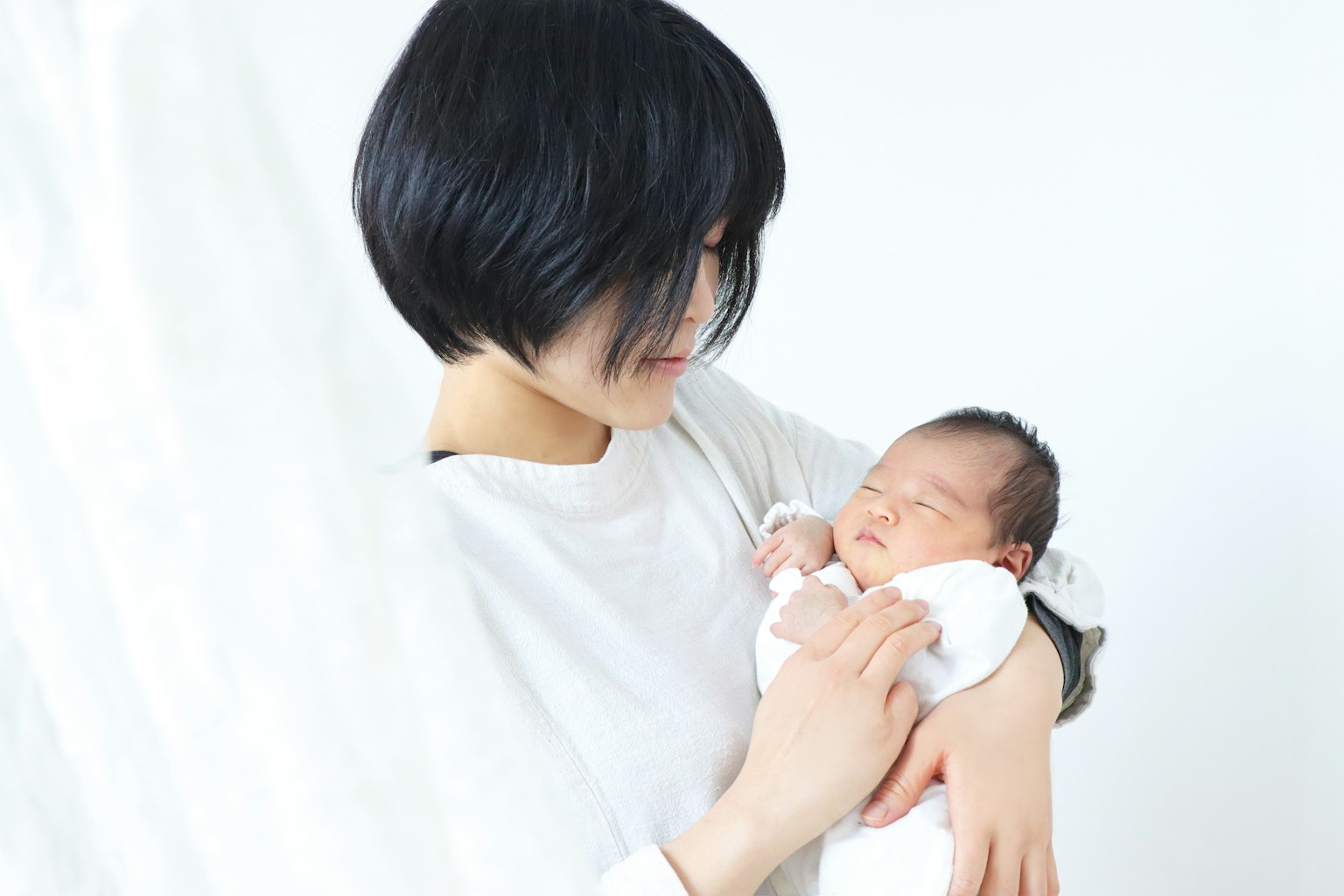Una donna che sorride mentre tiene un bambino su uno sfondo bianco