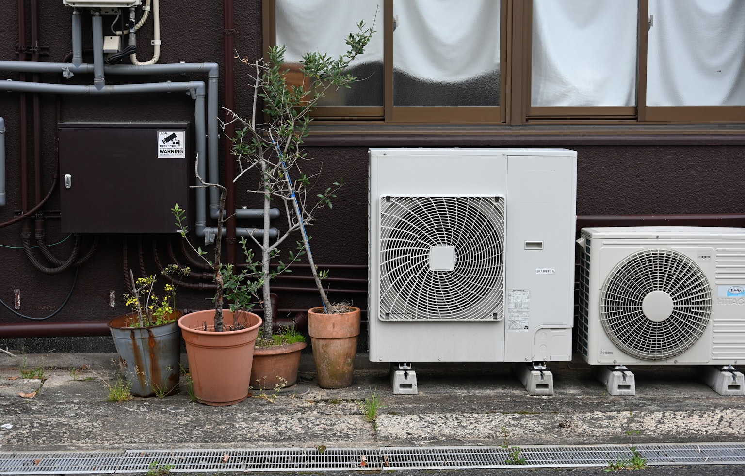 Una scena con unità di climatizzazione accanto a vasi di fiori contro un muro di edificio