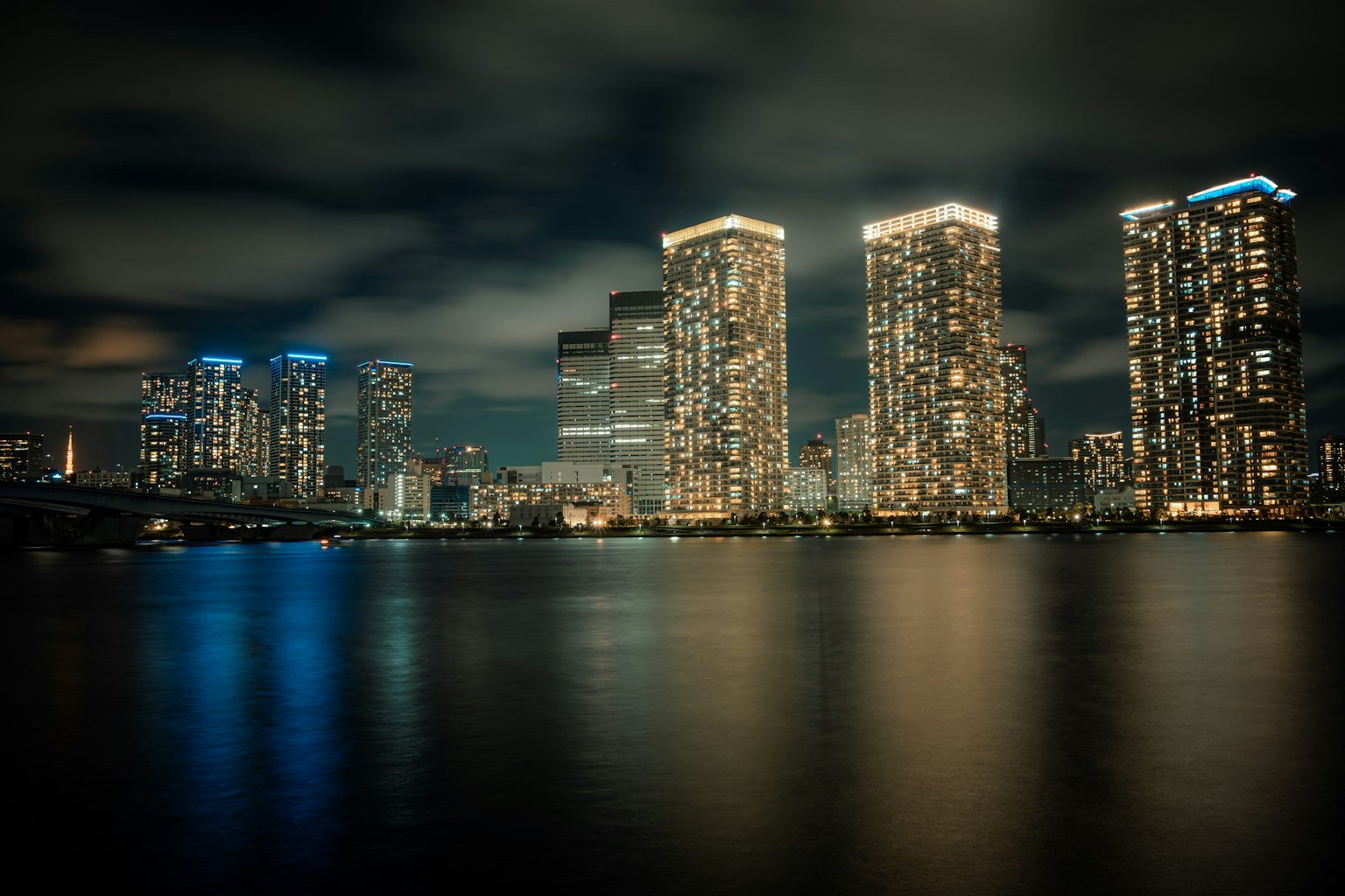Skyline della città con grattacieli illuminati che si riflettono sull'acqua di notte