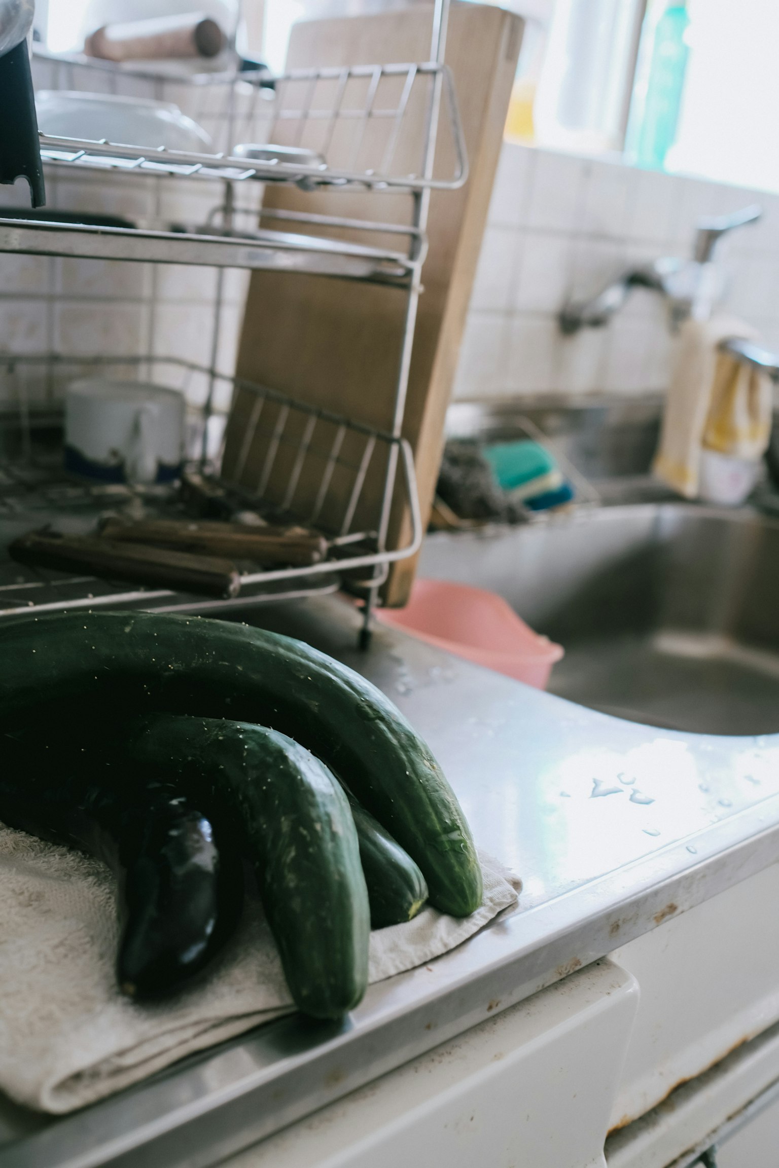 Concombres frais reposant sur une serviette près d'un évier de cuisine avec des ustensiles de cuisine en arrière-plan