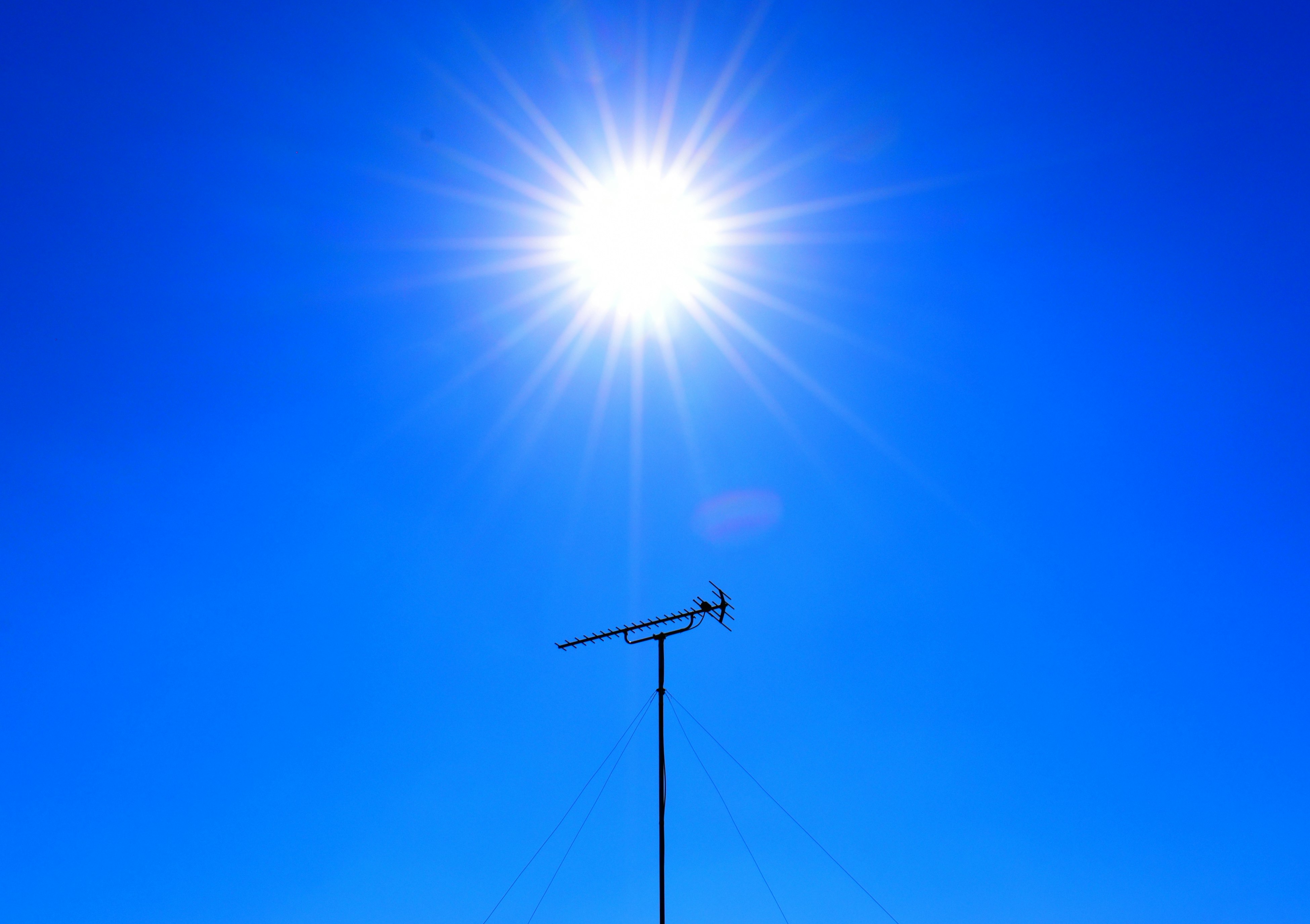 青空の下にそびえるアンテナと太陽の光
