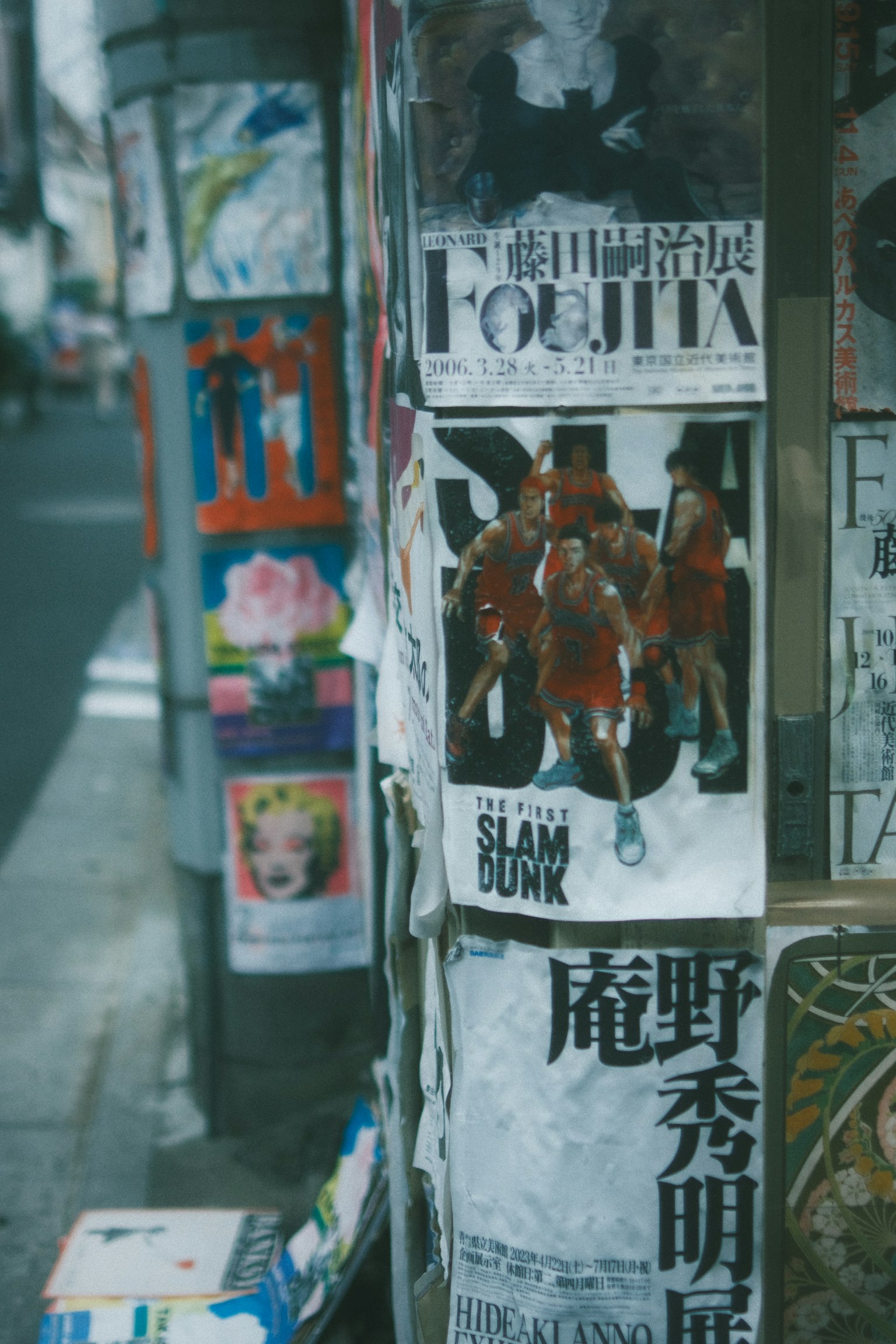 Poster di sudut jalan dengan karakter Slam Dunk dan berbagai iklan