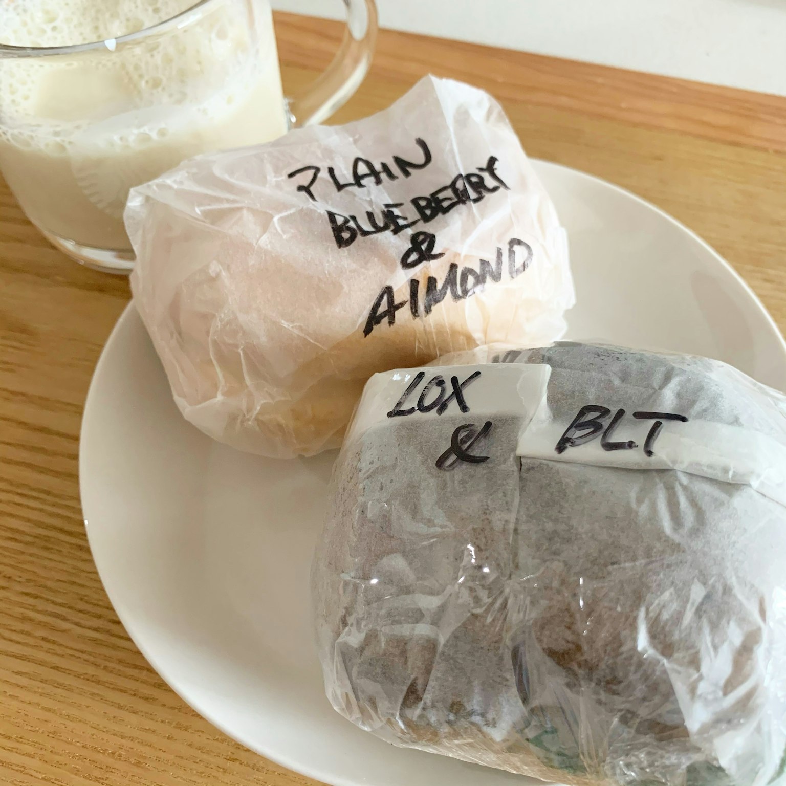Zwei eingewickelte Sandwiches auf einem Teller mit einem Glas Milch