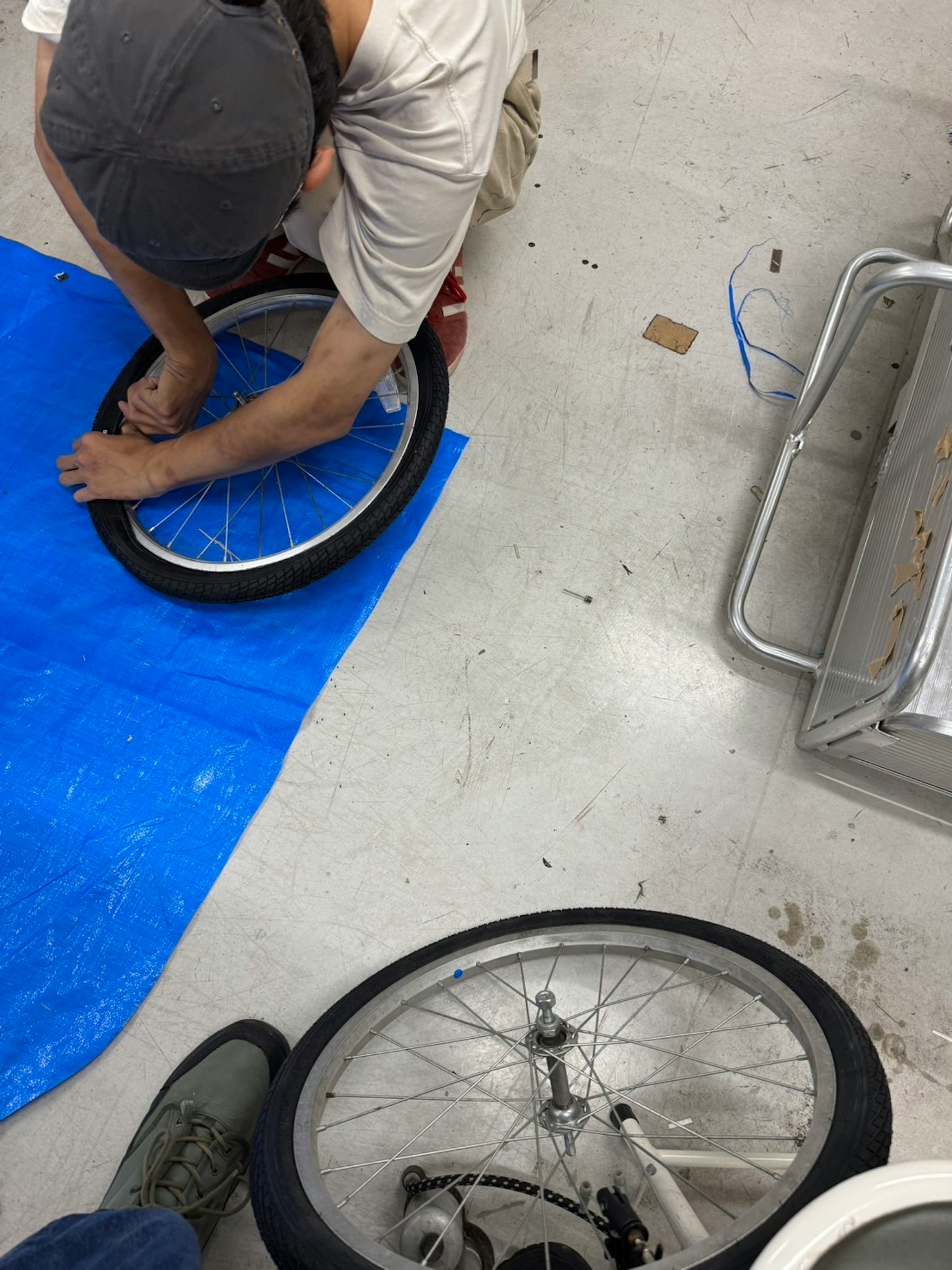 Persona reparando un neumático de bicicleta sobre una lona azul