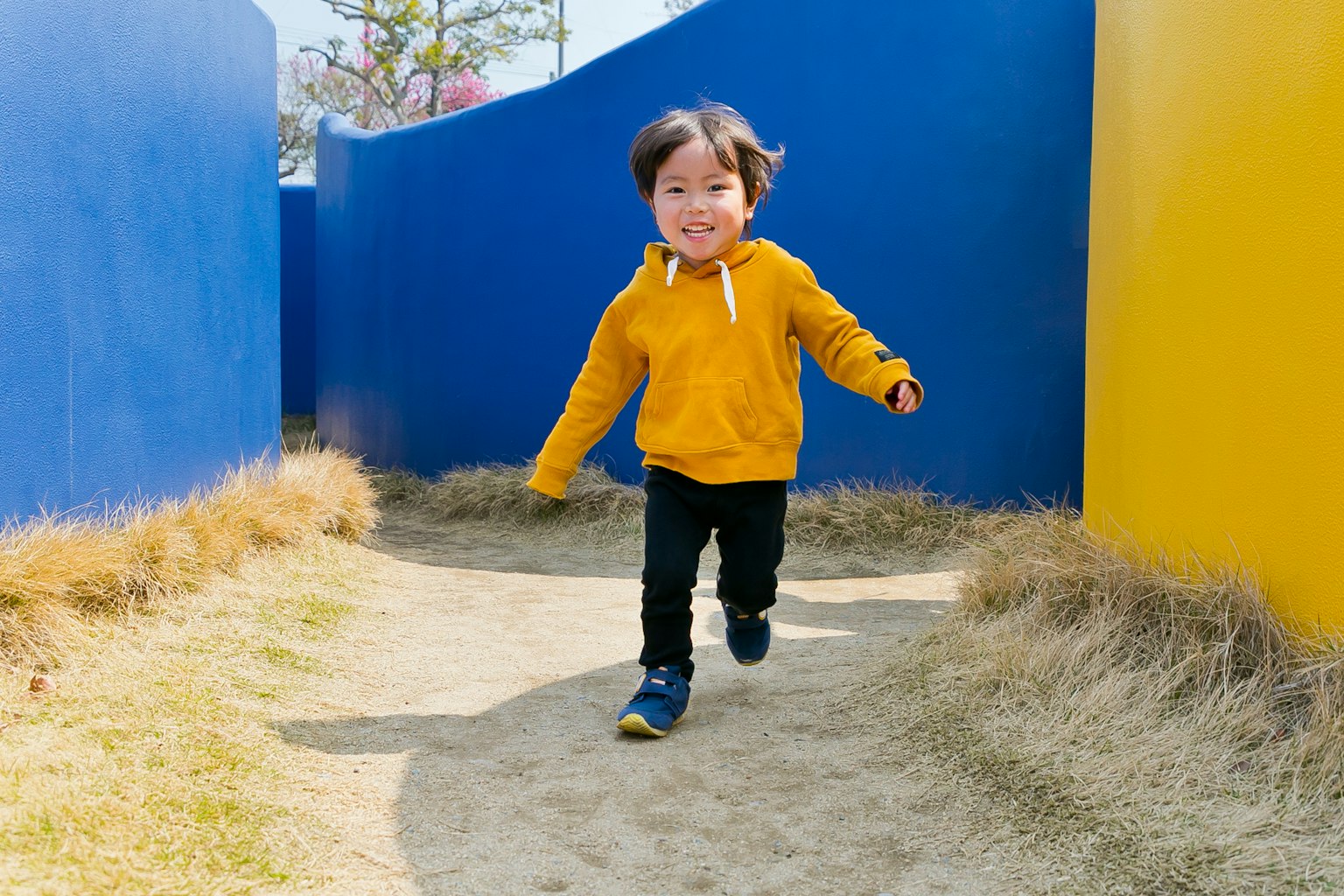Enfant courant sur un chemin entouré de murs bleus et jaunes