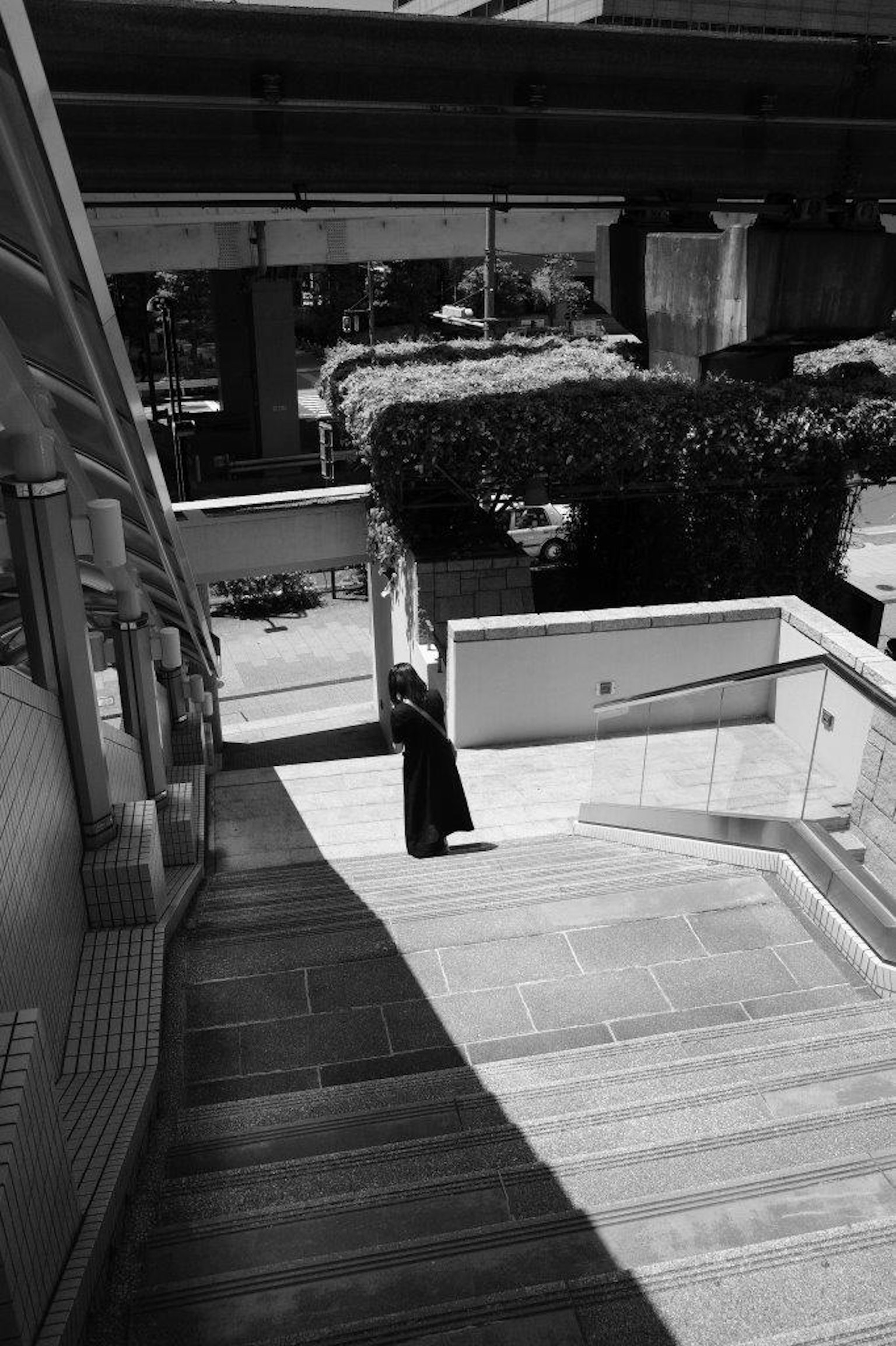 Silhouette einer Frau, die Treppen hinabsteigt, mit Betonstrukturen im Hintergrund