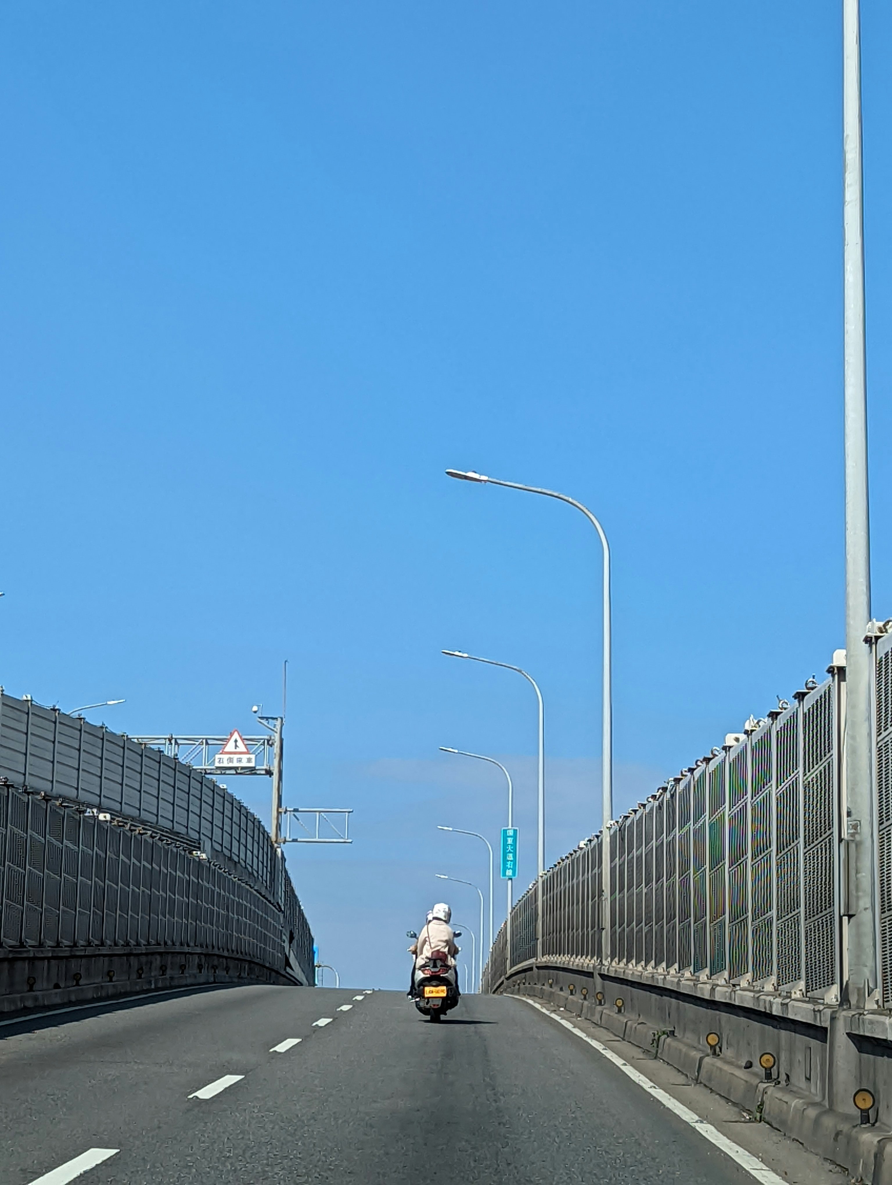 青空の下を走るバイクが見える高架の道路