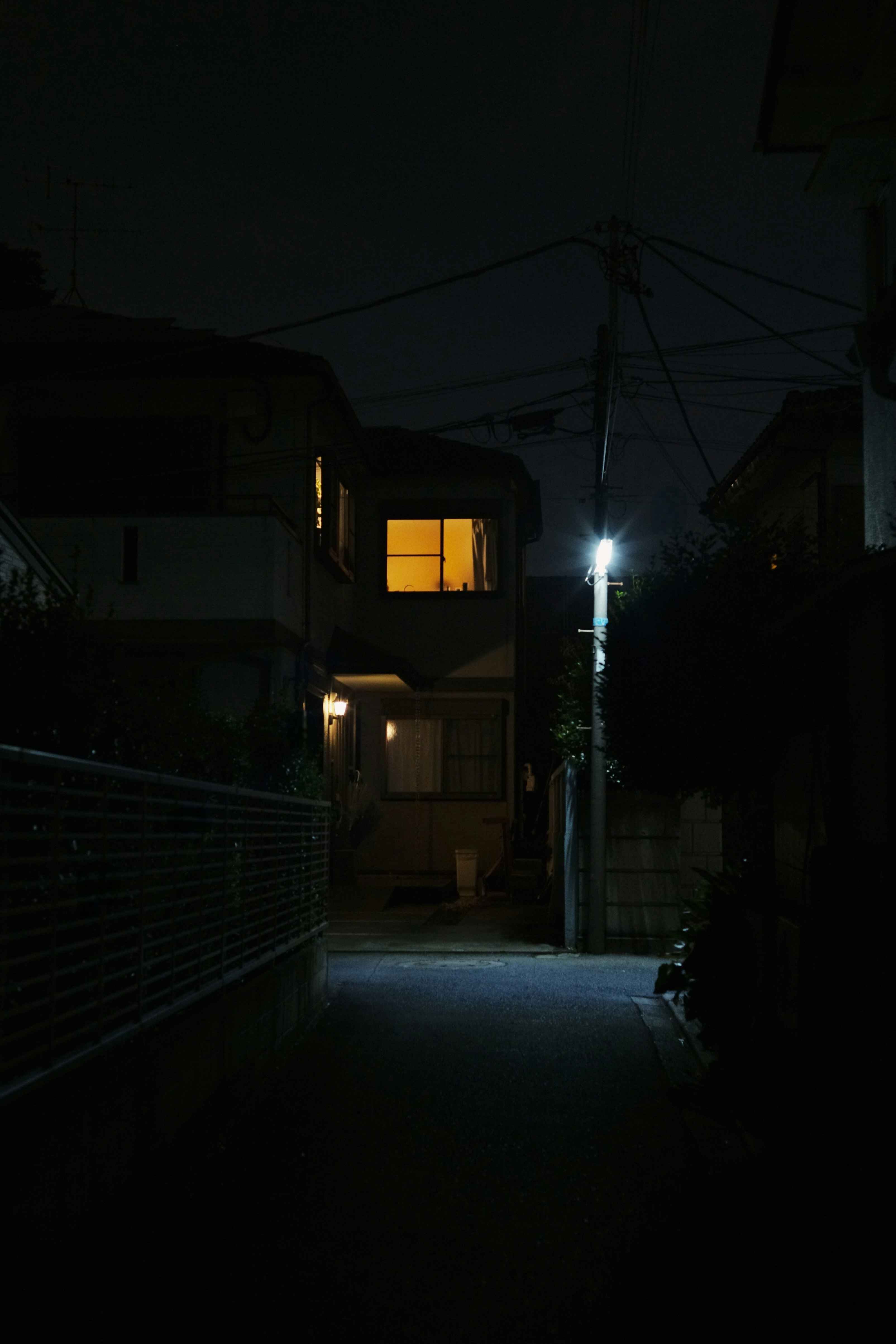 夜の路地に灯る街灯と家の窓の光