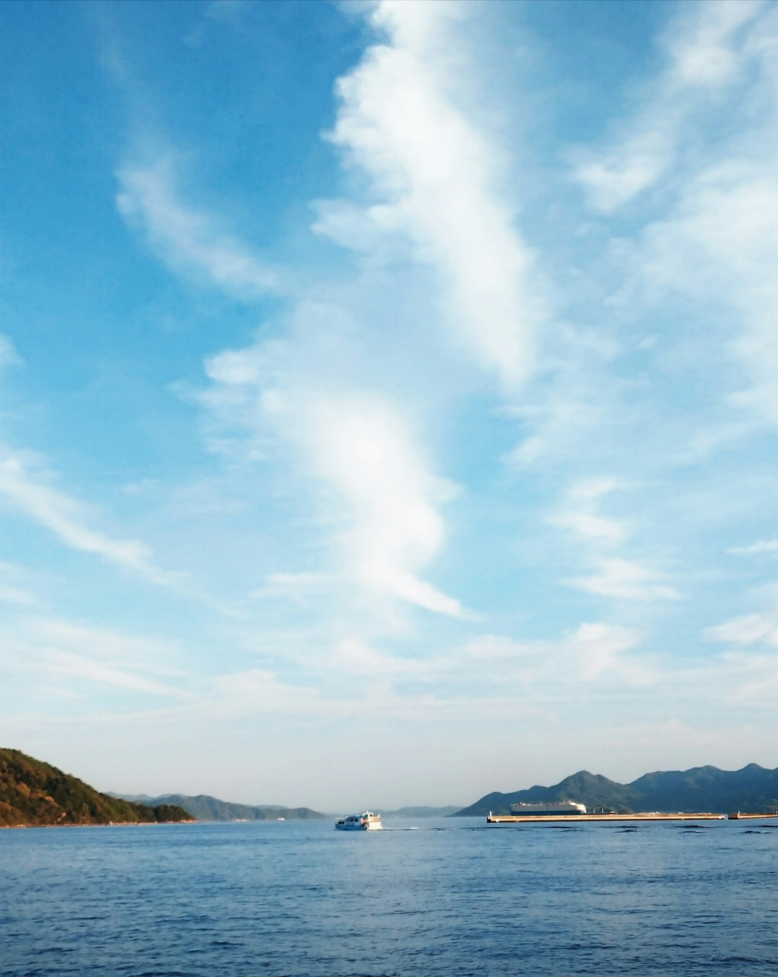 Vista escénica de un cielo azul con nubes blancas sobre un mar tranquilo un barco navegando a lo lejos