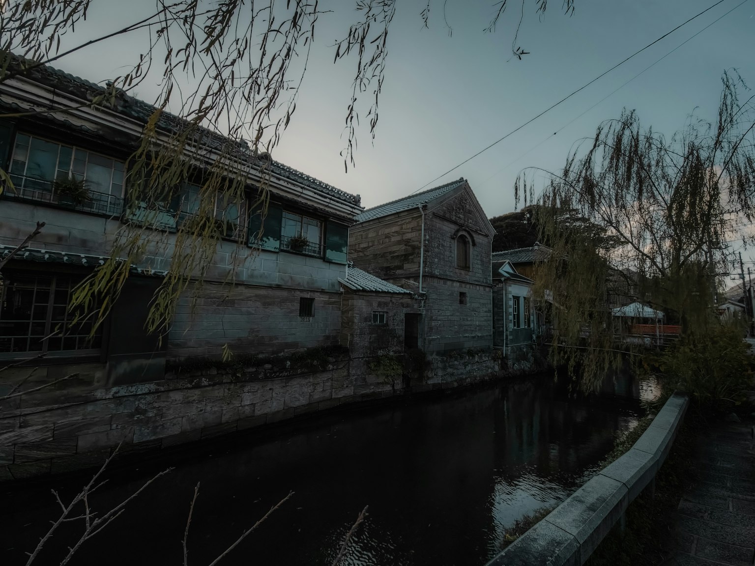 Una escena tranquila con edificios antiguos a lo largo de un canal y sauces